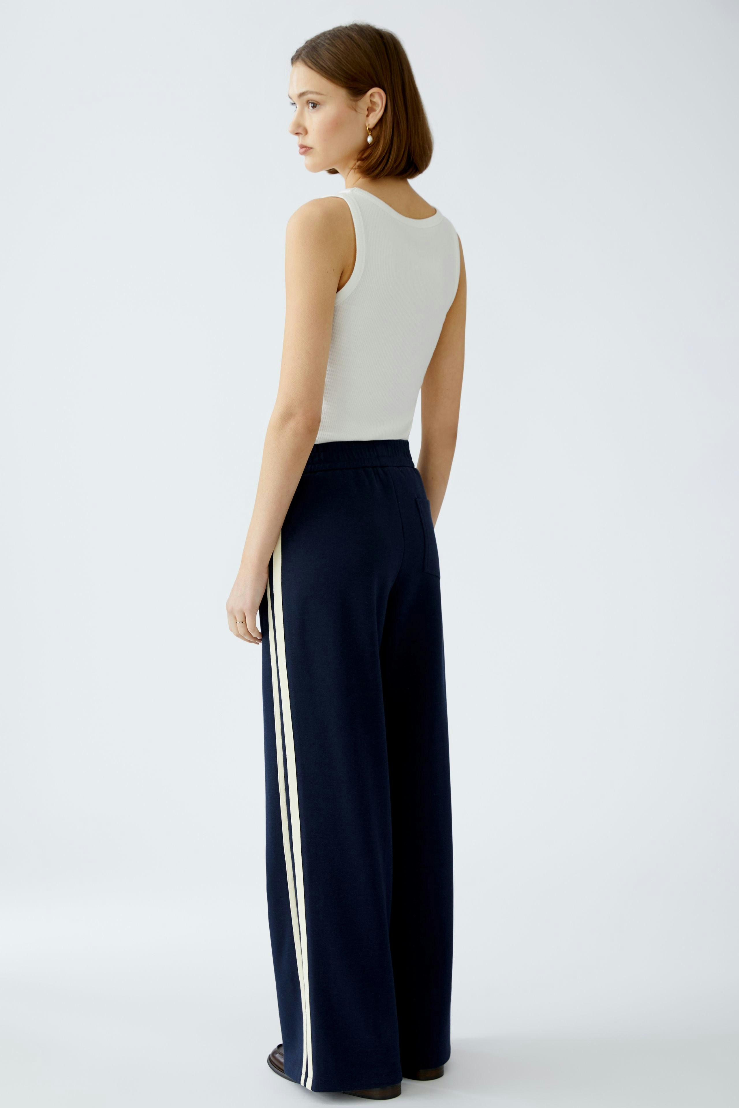 Stylish women's pants: A woman in navy wide-leg pants with white stripes, showcasing a modern look.