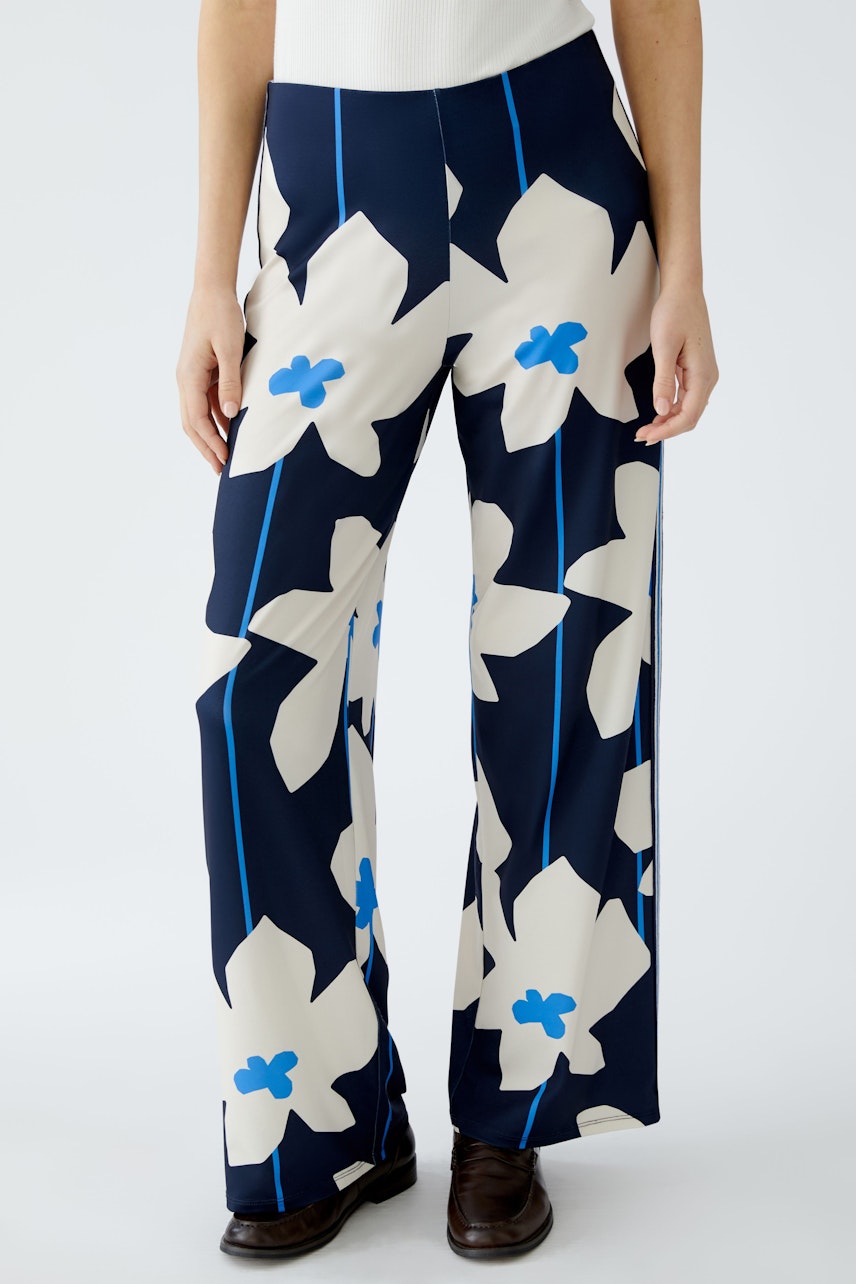 Moderne Damen-Hose: Frau in blauen, floral gemusterten, weiten Hosen mit eleganten Details.