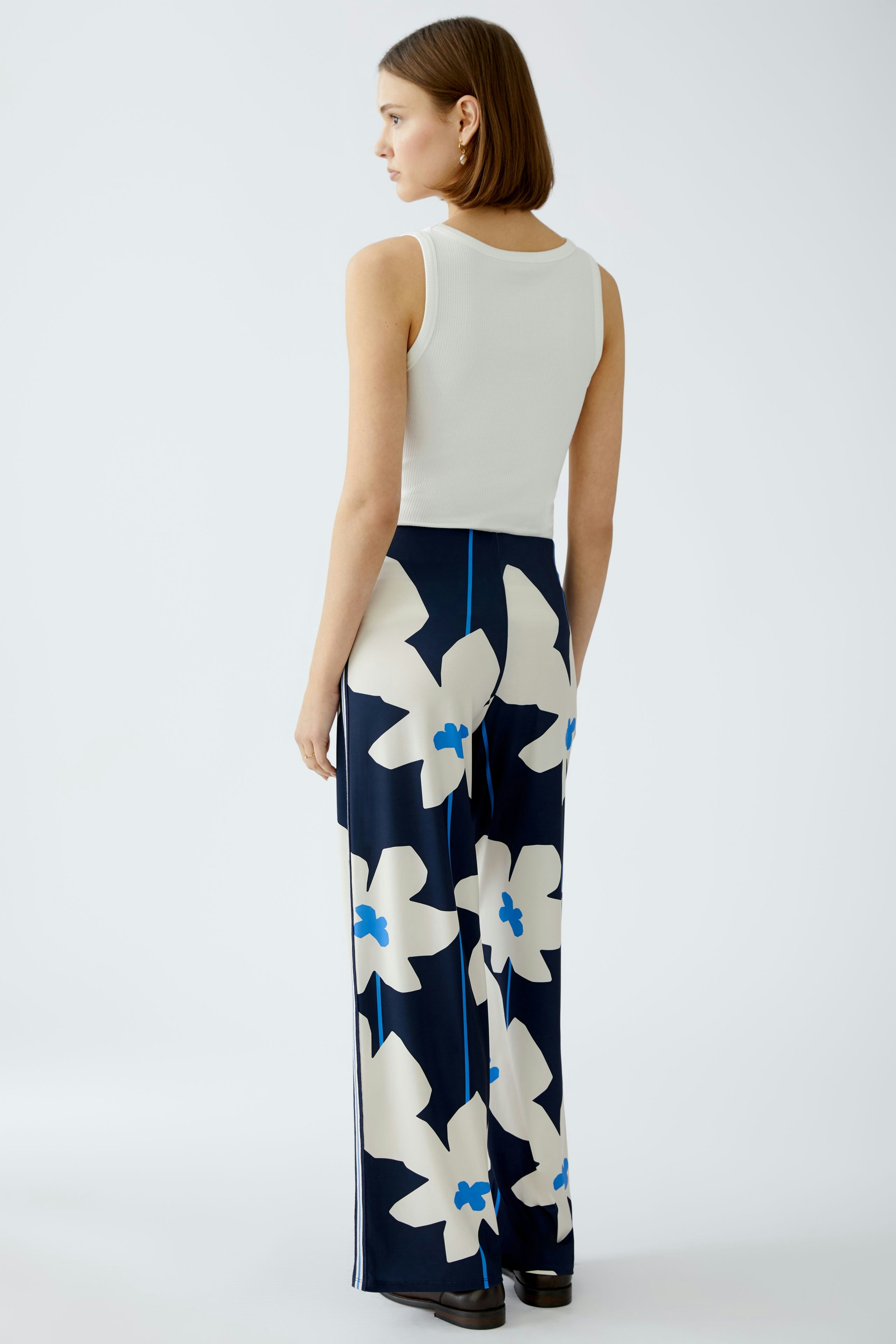 Stylish women's trousers: A woman in floral-patterned wide-leg pants, showcasing a modern design.