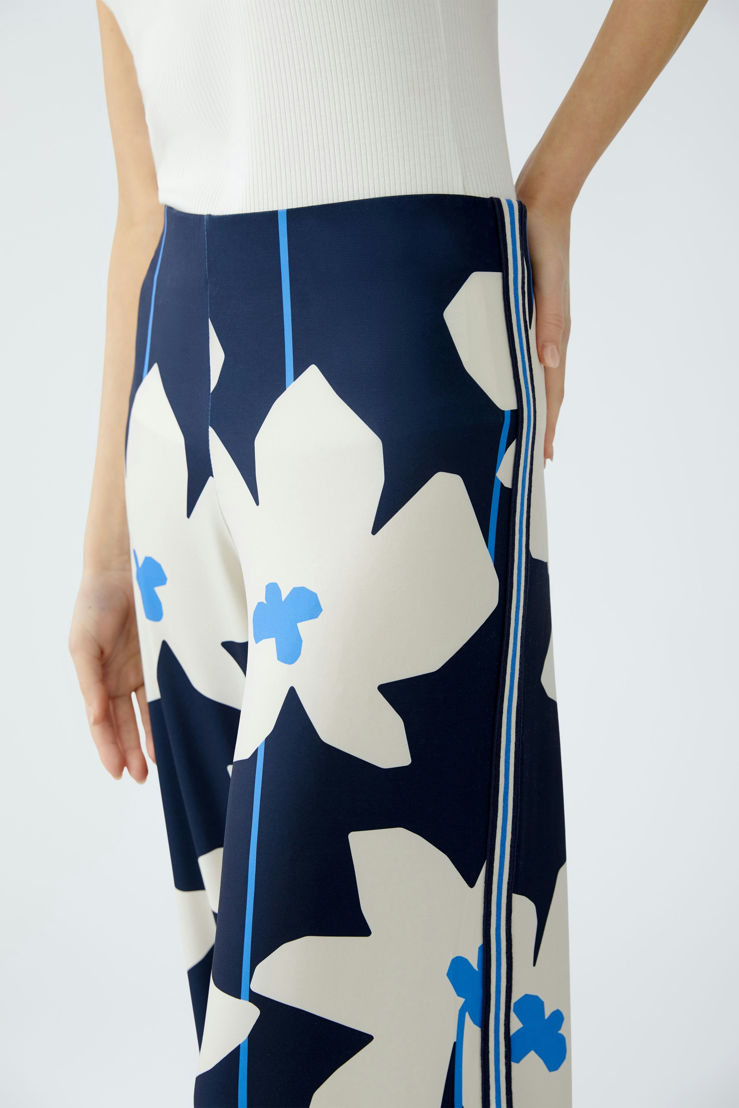 Stylish women's trousers: Close-up of a woman wearing floral-patterned pants with a modern design.