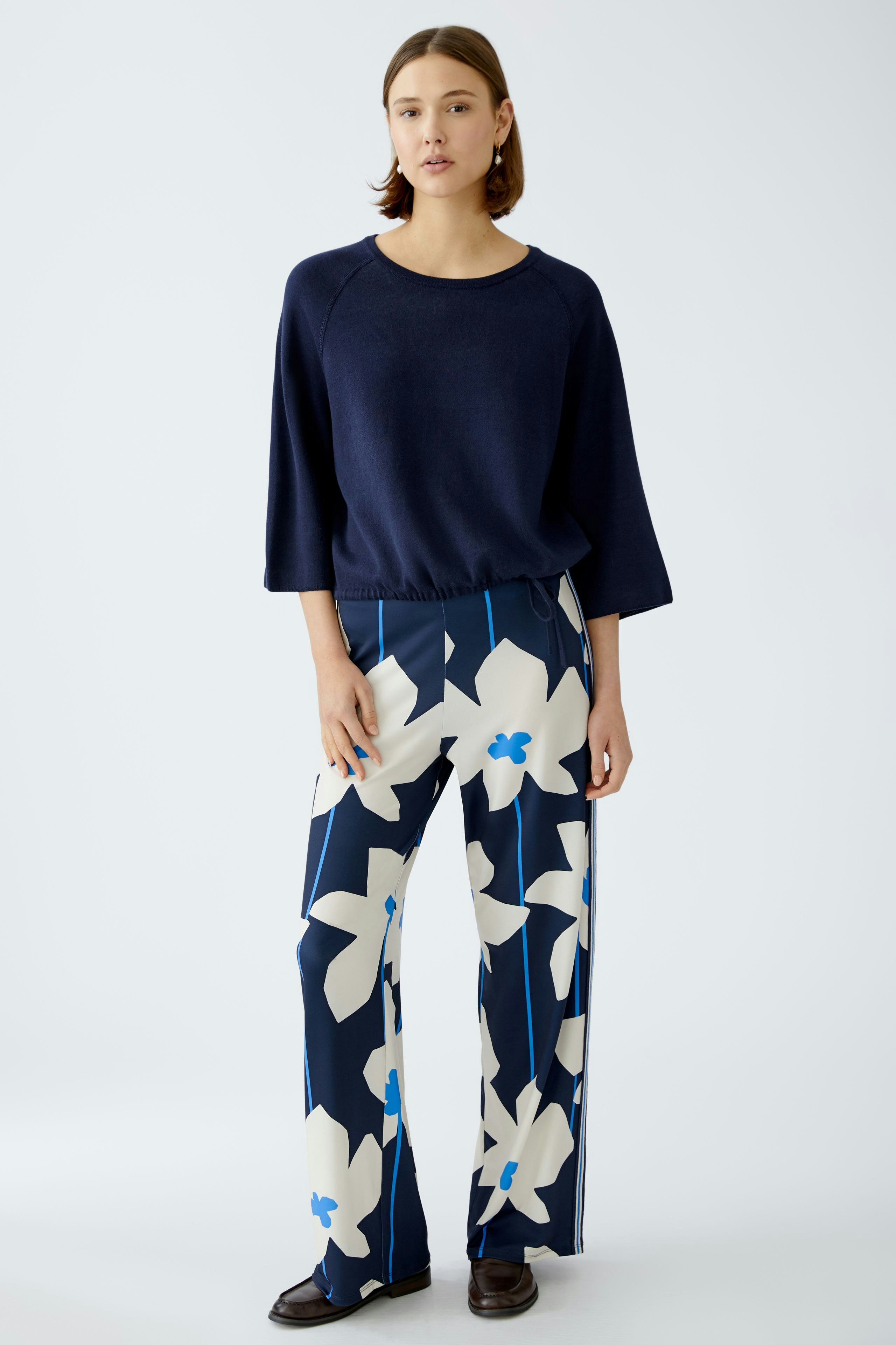 Stylish women's pants: A woman in floral wide-leg trousers stands confidently against a light background.