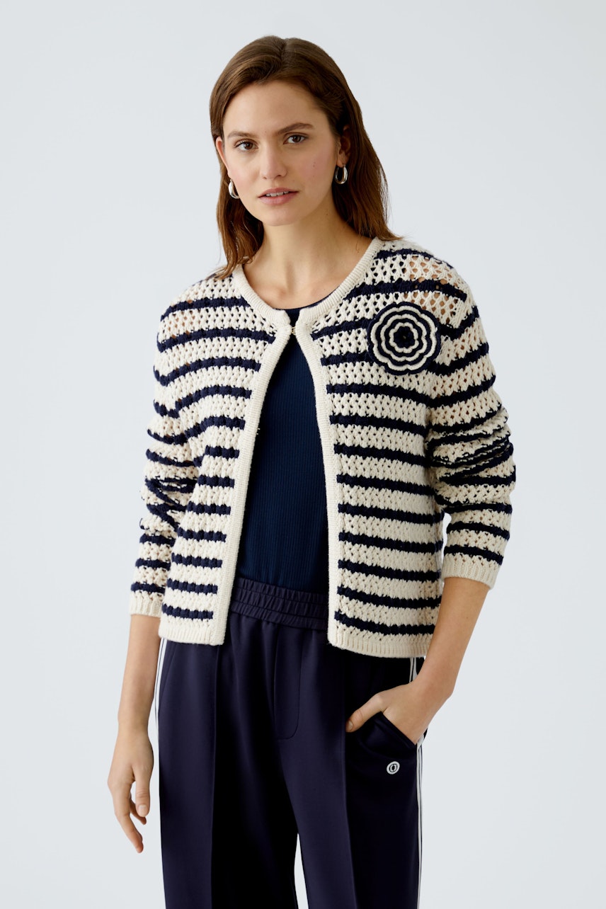 Gestreifte Damen-Strickjacke: Frau in navy-weißer Jacke mit Blumenmotiv und lässigem Look.