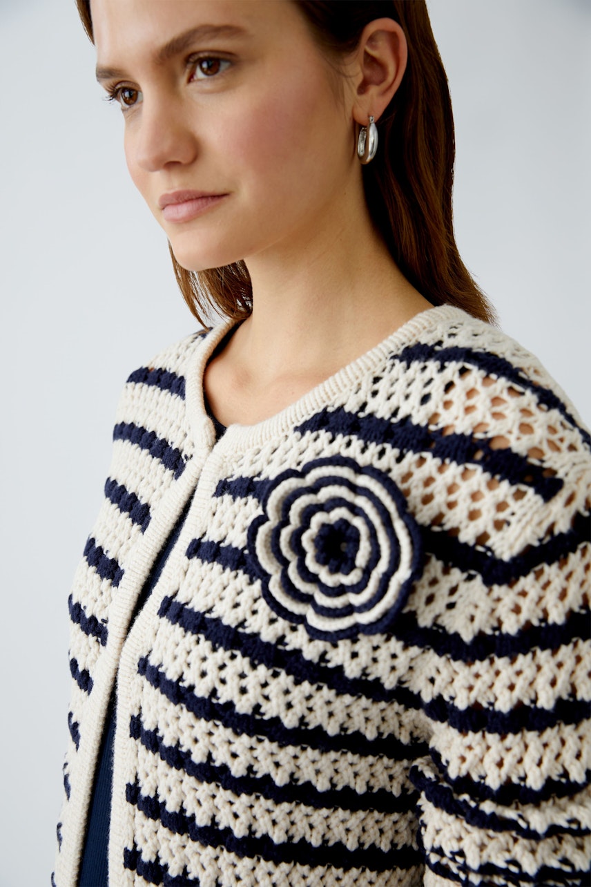 Stylish women's cardigan: A woman in a striped knit cardigan with a floral detail, exuding elegance.