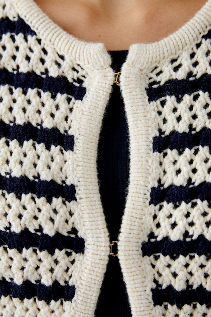 Stylish women's cardigan: Close-up of a woman wearing a cream and navy striped knitted cardigan.