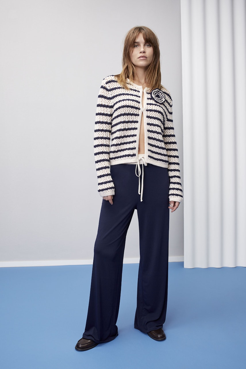 Stylish women's cardigan: A woman in a striped cardigan with a drawstring, paired with navy trousers.