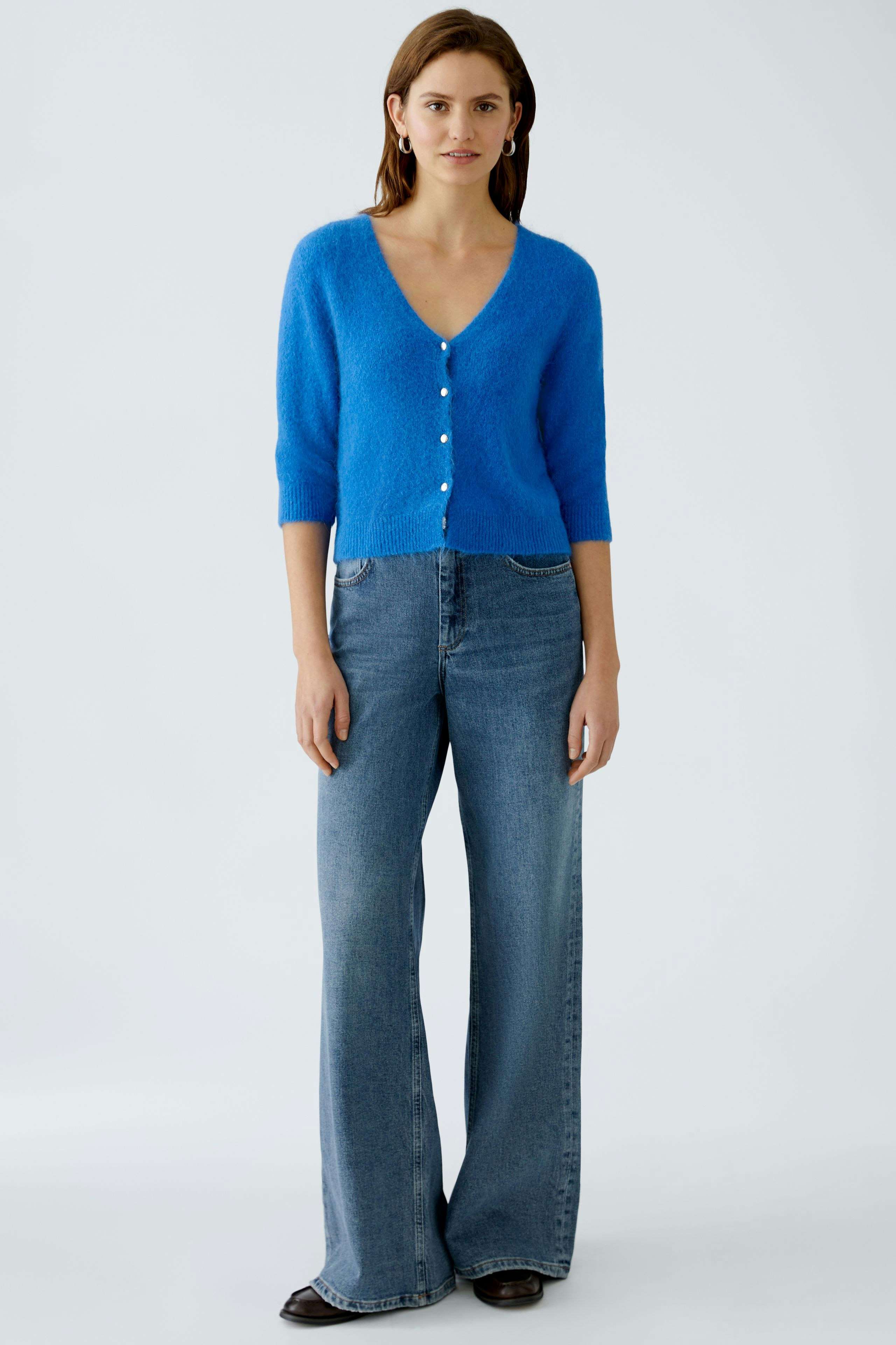 Helle Damen-Strickjacke in Blau mit Knöpfen, kombiniert mit lässigen Jeans.