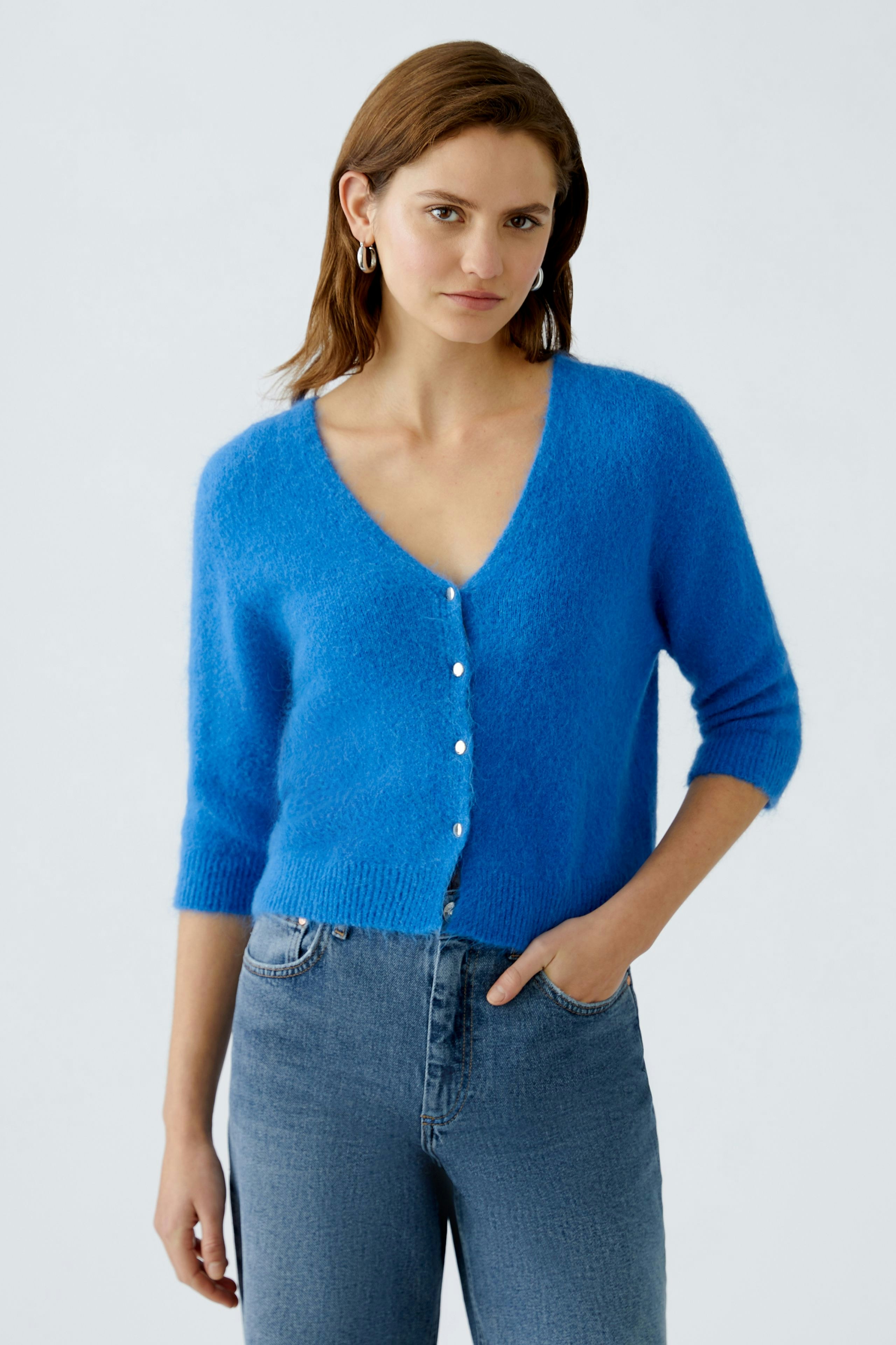 Helle Damen-Strickjacke in Blau mit Knöpfen, kombiniert mit Jeans für einen lässigen Look.