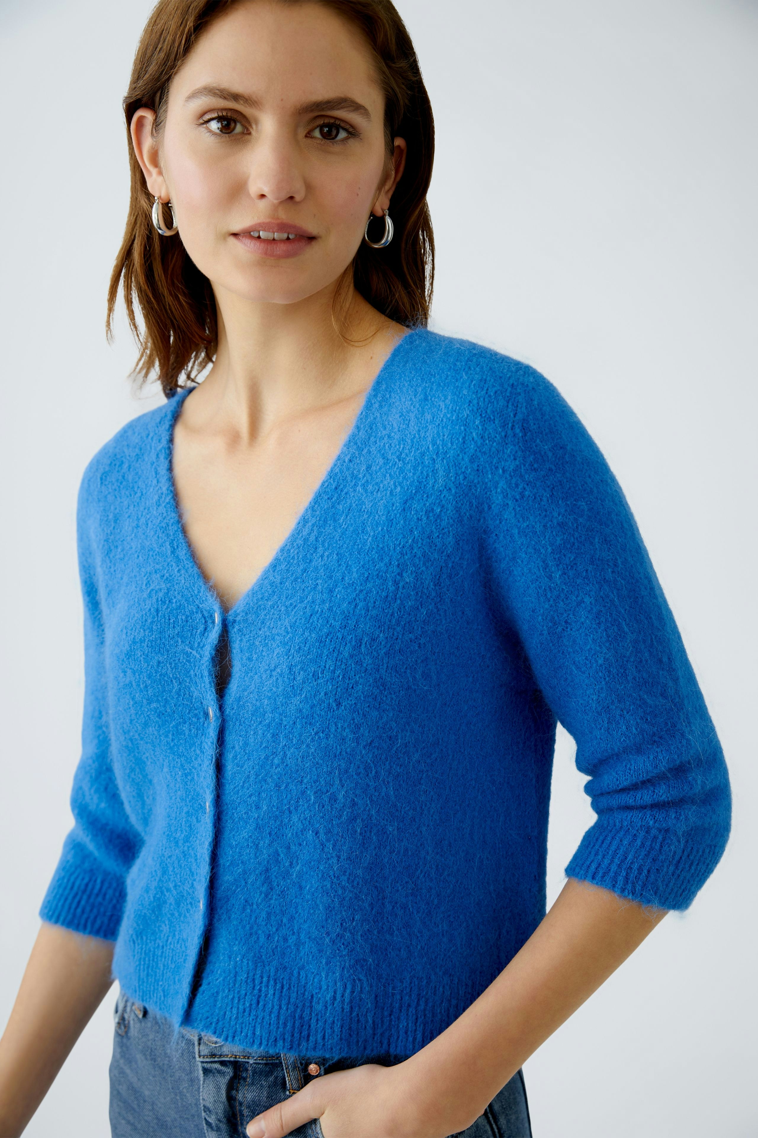 Damen-Strickjacke: Frau in blauer Strickjacke mit V-Ausschnitt und kurzen Ärmeln, lässig und modern.