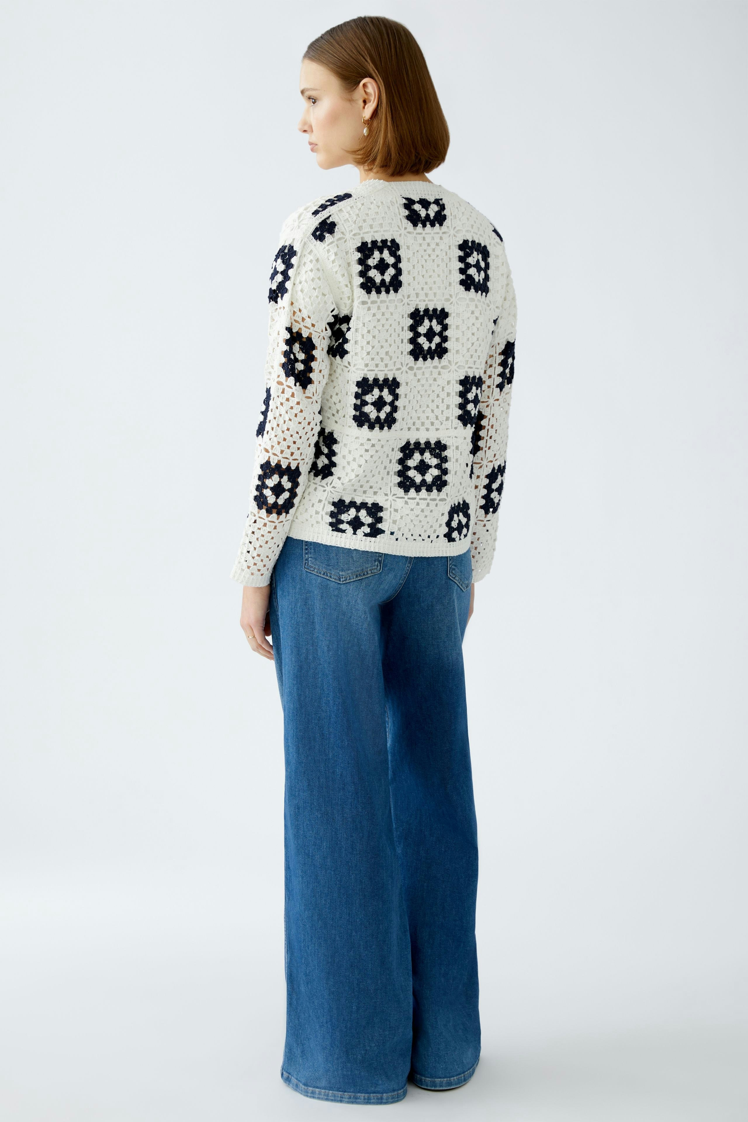 Stylish women's cardigan: A woman in a patterned knit cardigan paired with wide-leg jeans.
