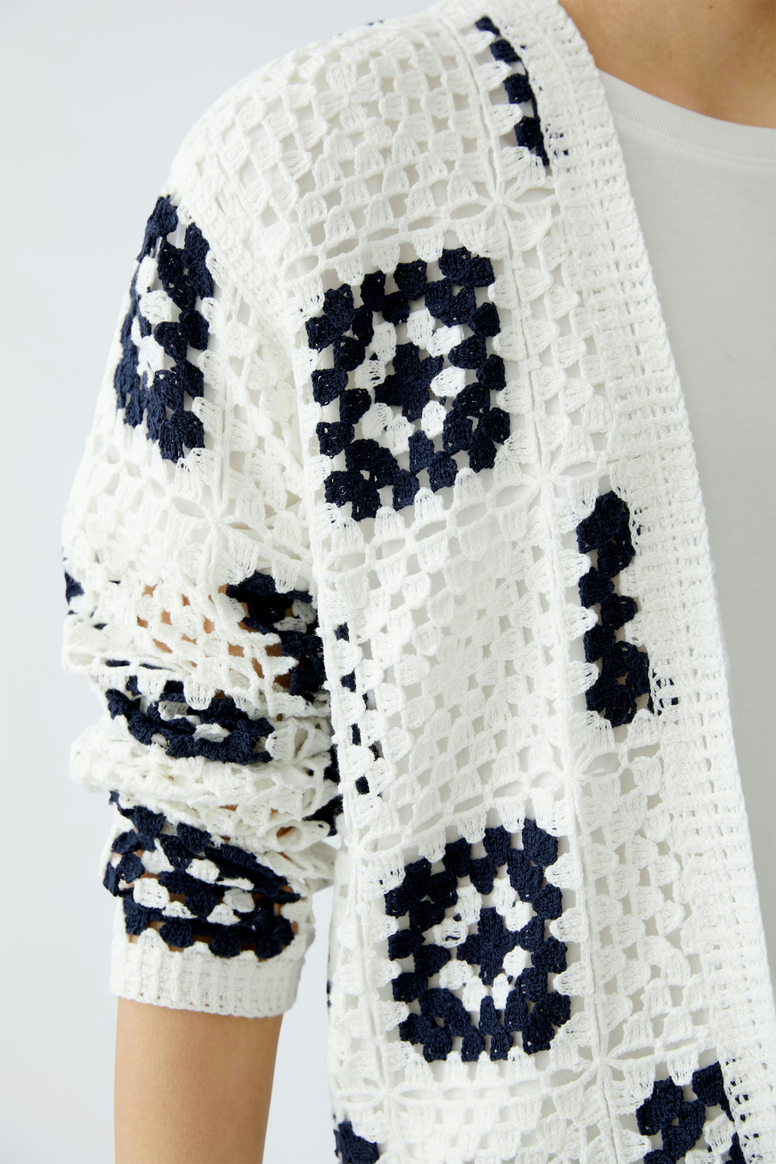 Stylish women's cardigan: A woman in a white and navy patterned knitted cardigan.
