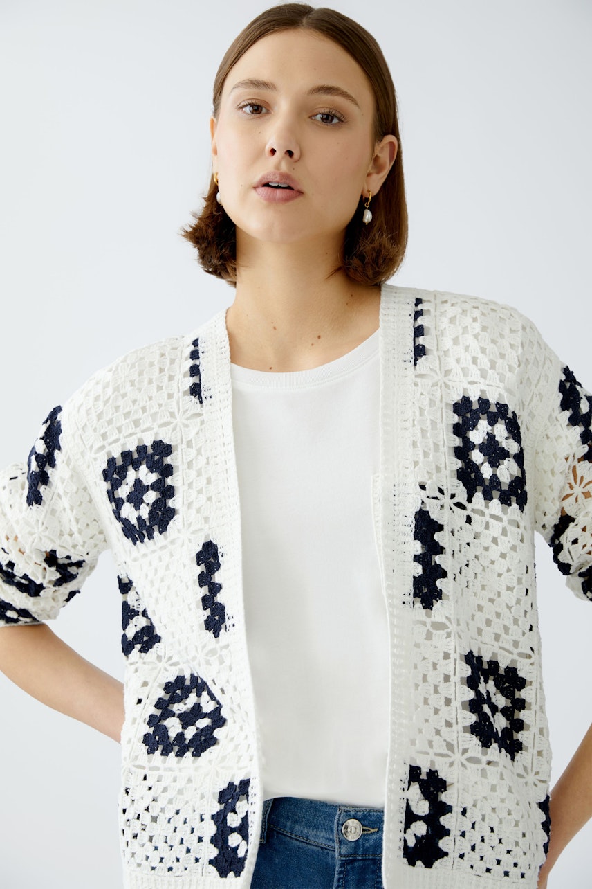 Stylish women's cardigan: A woman in a white and navy patterned cardigan over a simple tee.