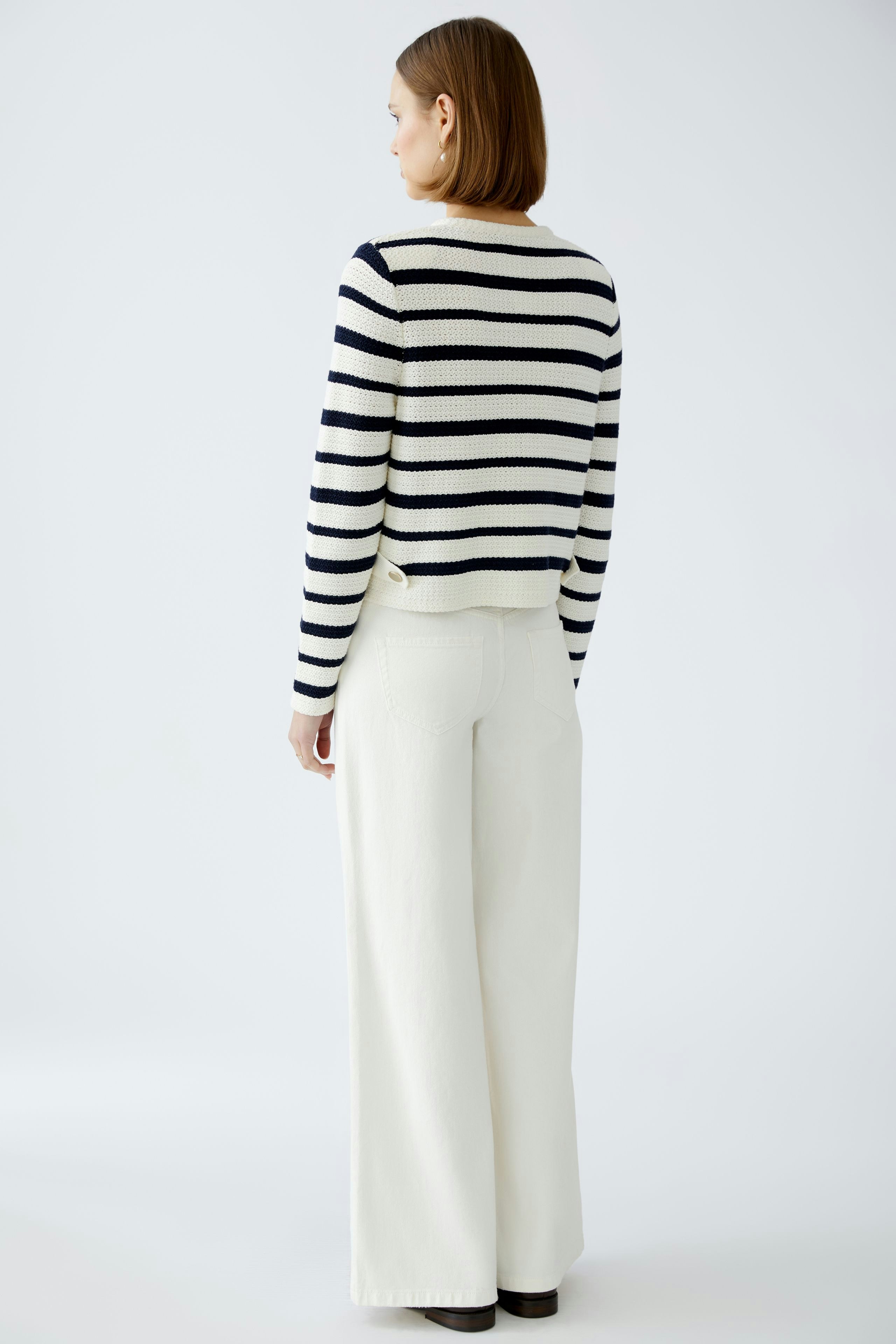 Stylish women's cardigan: A woman in a striped pullover with a relaxed fit, paired with wide-leg pants.