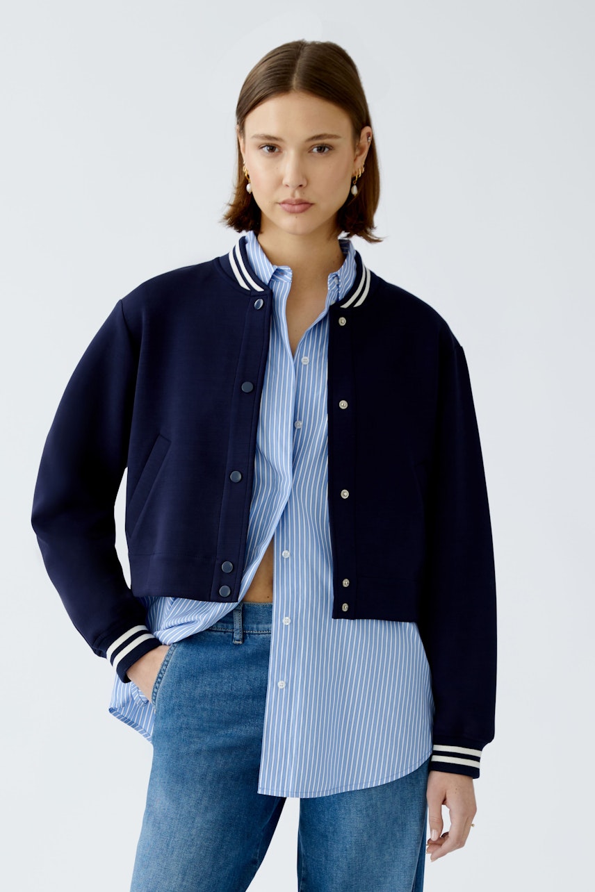 Damen-Blouson: Junge Frau in navy Blouson mit gestreifter Bluse und lässigen Jeans.