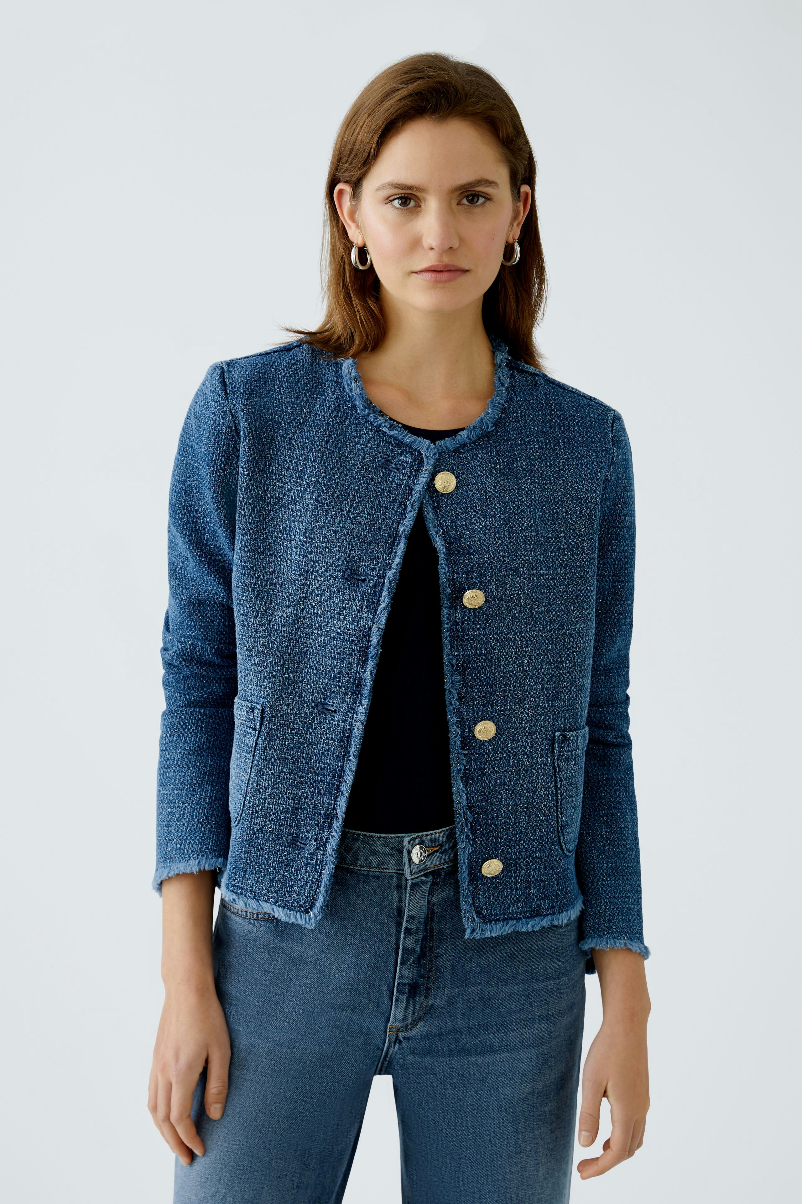 Chic women's jacket: A woman in a blue textured jacket with gold buttons, paired with jeans.