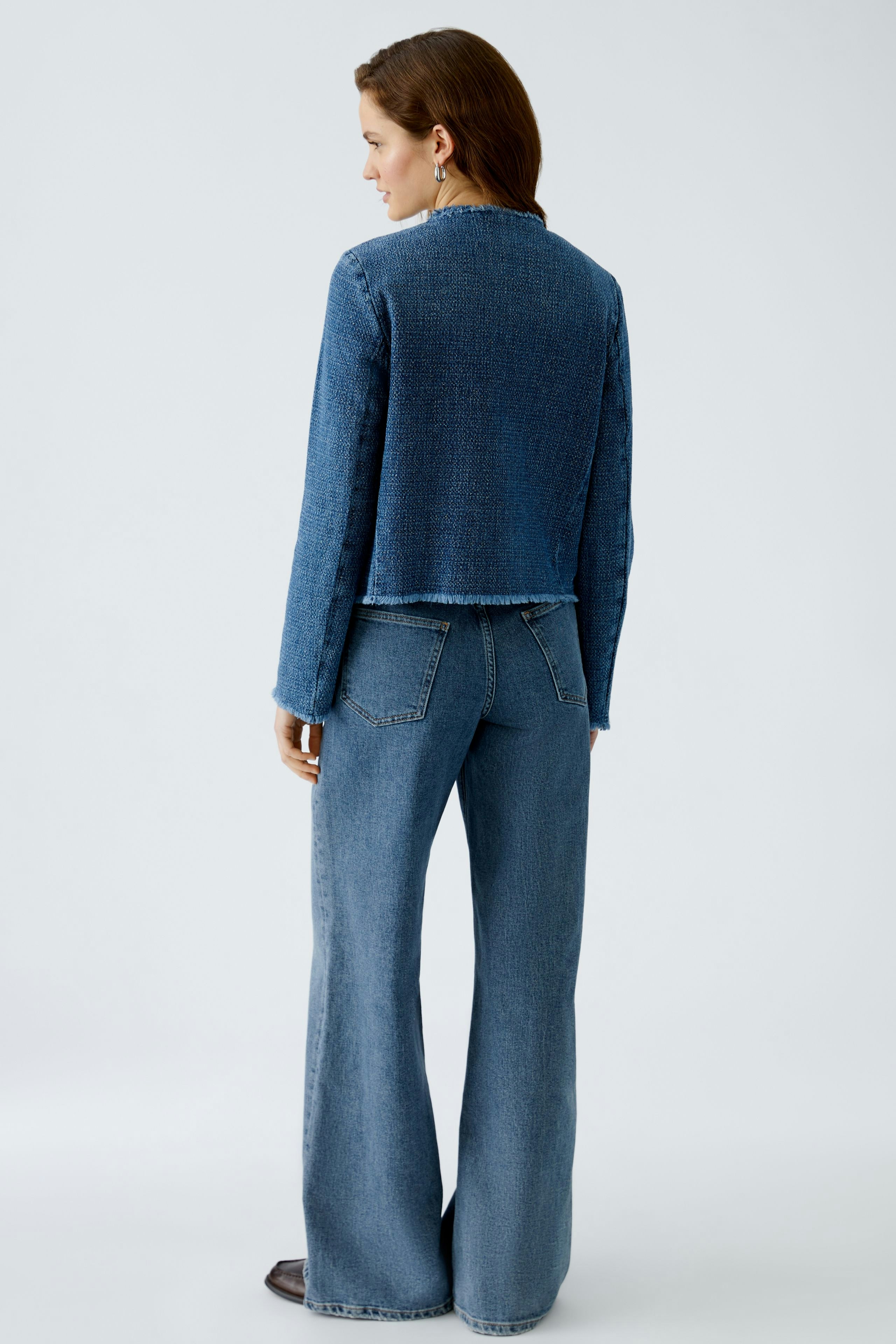 Stylish women's jacket: A woman in a cropped denim jacket paired with flared jeans.