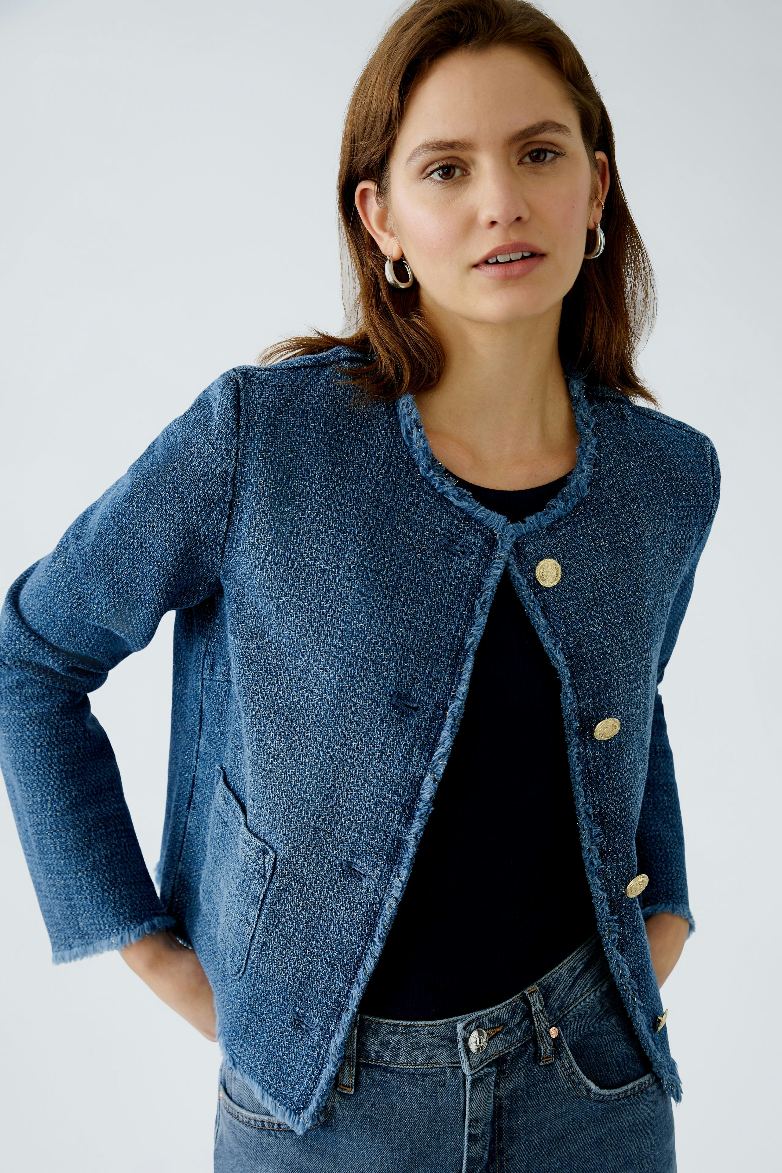 Stylish women's jacket: A woman in a blue textured jacket with gold buttons, paired with a black top.