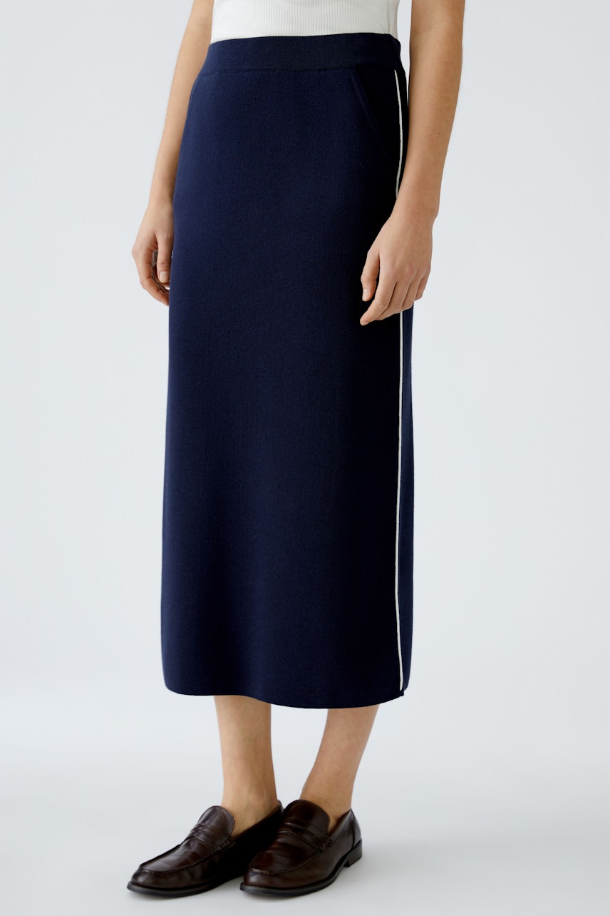 Elegant navy knitted skirt: A woman stands confidently, showcasing a stylish, long skirt with a sleek design.