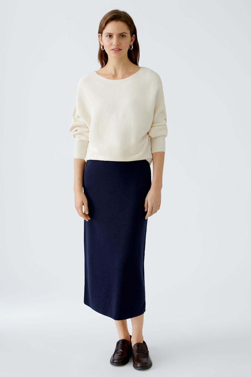 Elegant women's knitted skirt: A woman in a navy skirt paired with a cream pullover, exuding sophistication.