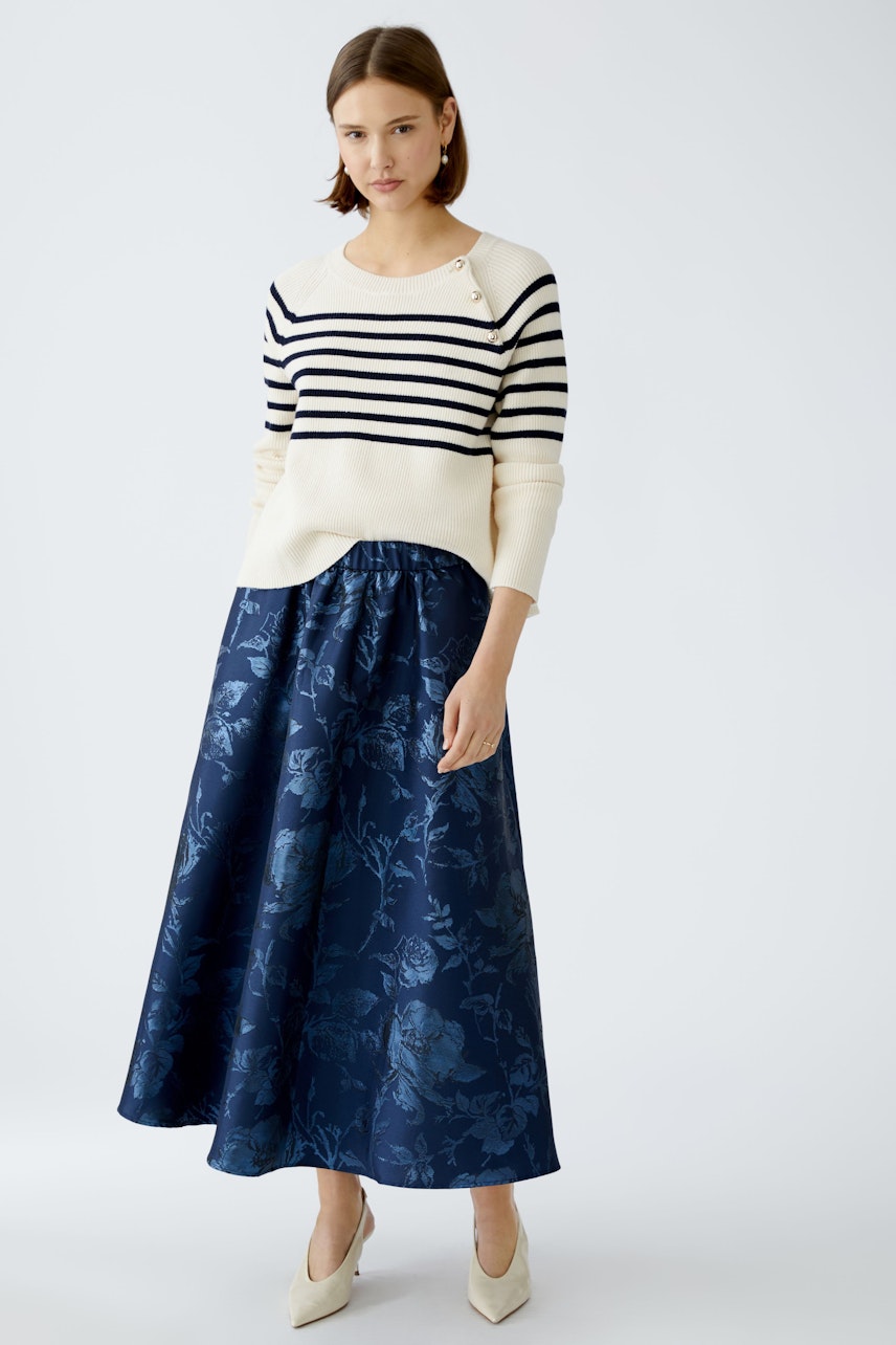 Elegant maxi skirt: A woman in a flowing navy floral maxi skirt paired with a stylish striped pullover.