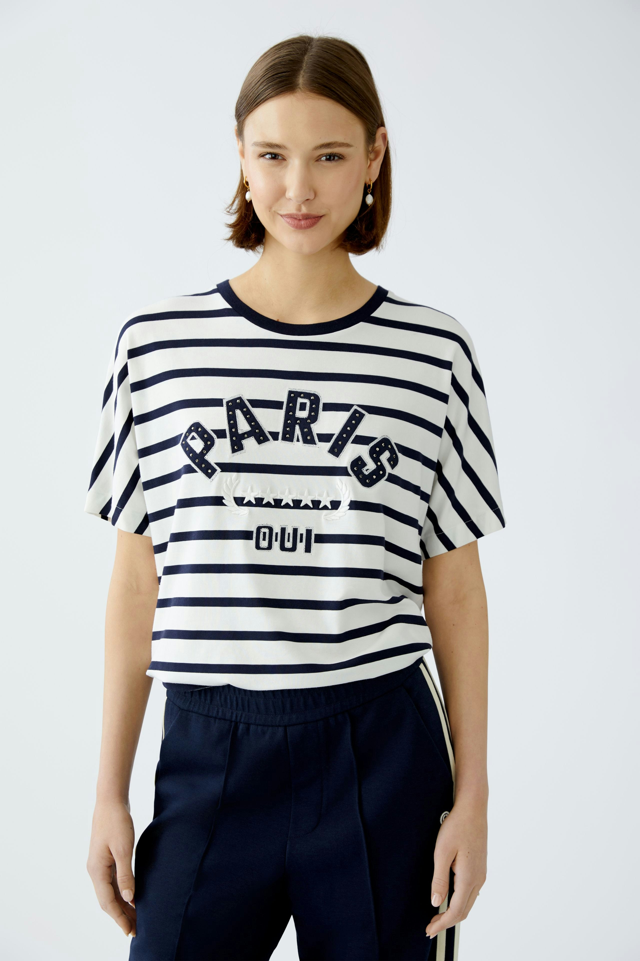 Stylish women's T-shirt: A woman in a striped tee with 'PARIS' print, exuding casual elegance.