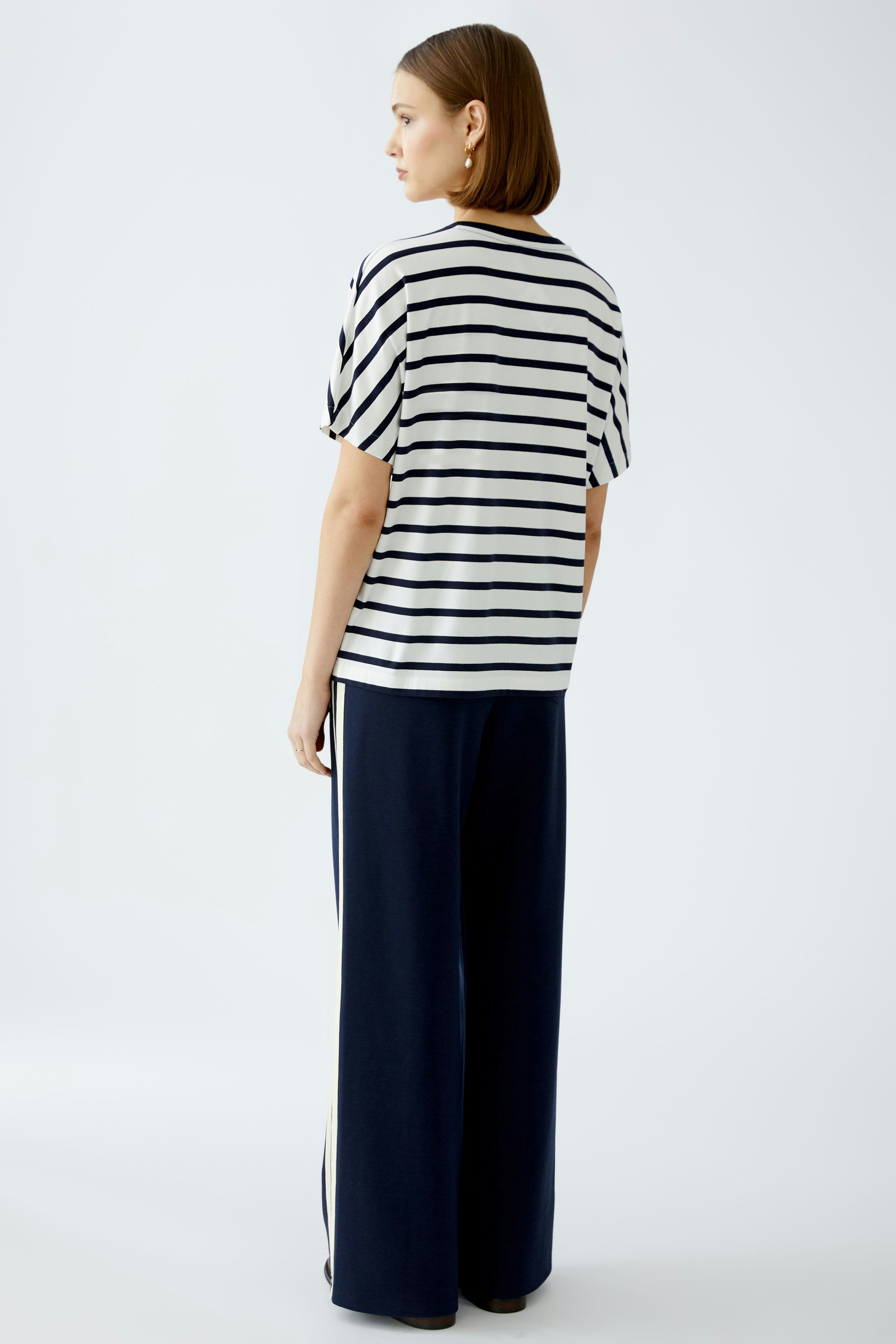 Stylish women's T-shirt: A woman in a striped tee, paired with wide-leg pants, exudes casual elegance.