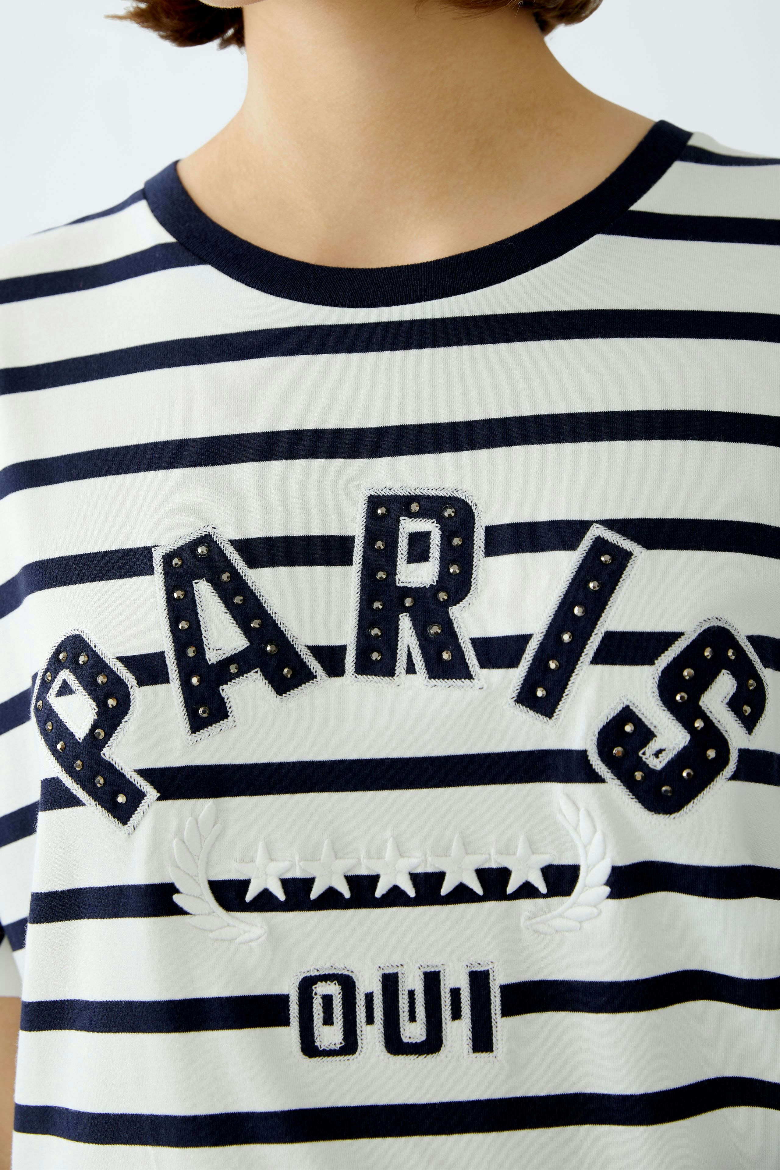 Stylish women's T-shirt: A woman in a striped tee featuring 'PARIS OUI' in bold letters.