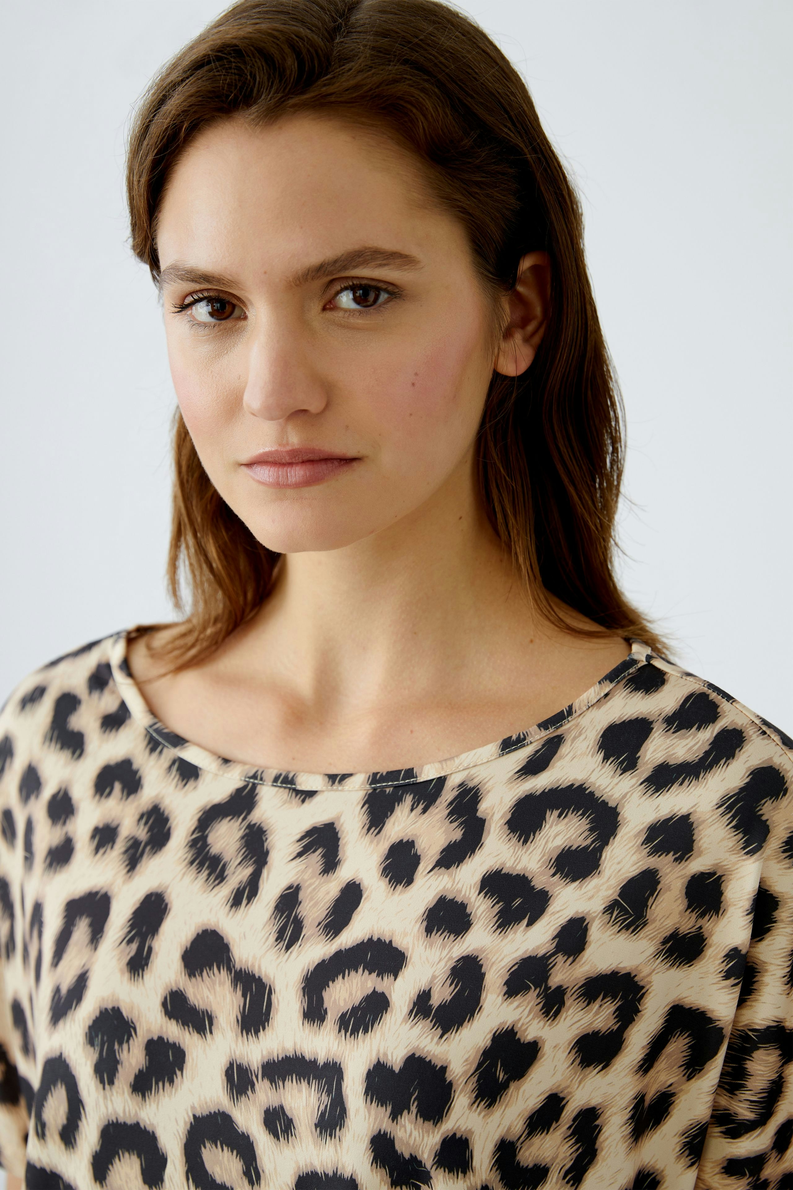 Stylish women's T-shirt: A woman in a leopard print top, exuding confidence and modern flair.