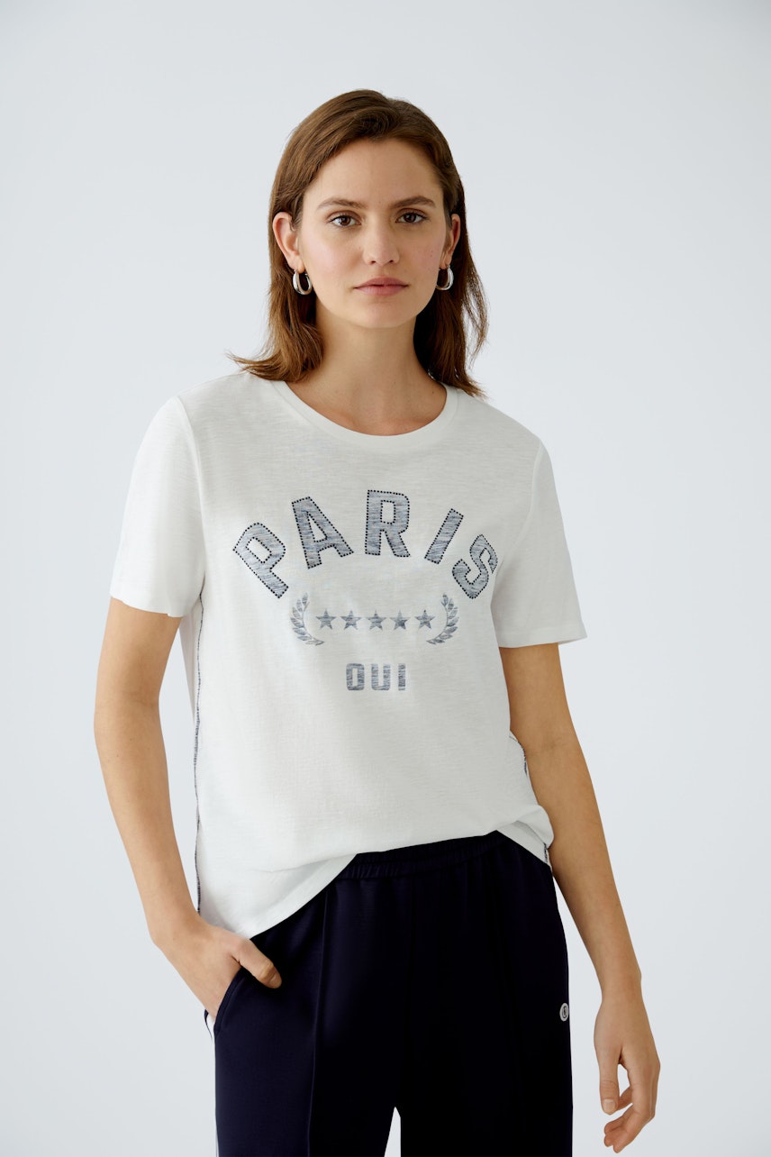 Stylish women's T-shirt: A woman in a light shirt with 'PARIS' print, paired with navy pants.