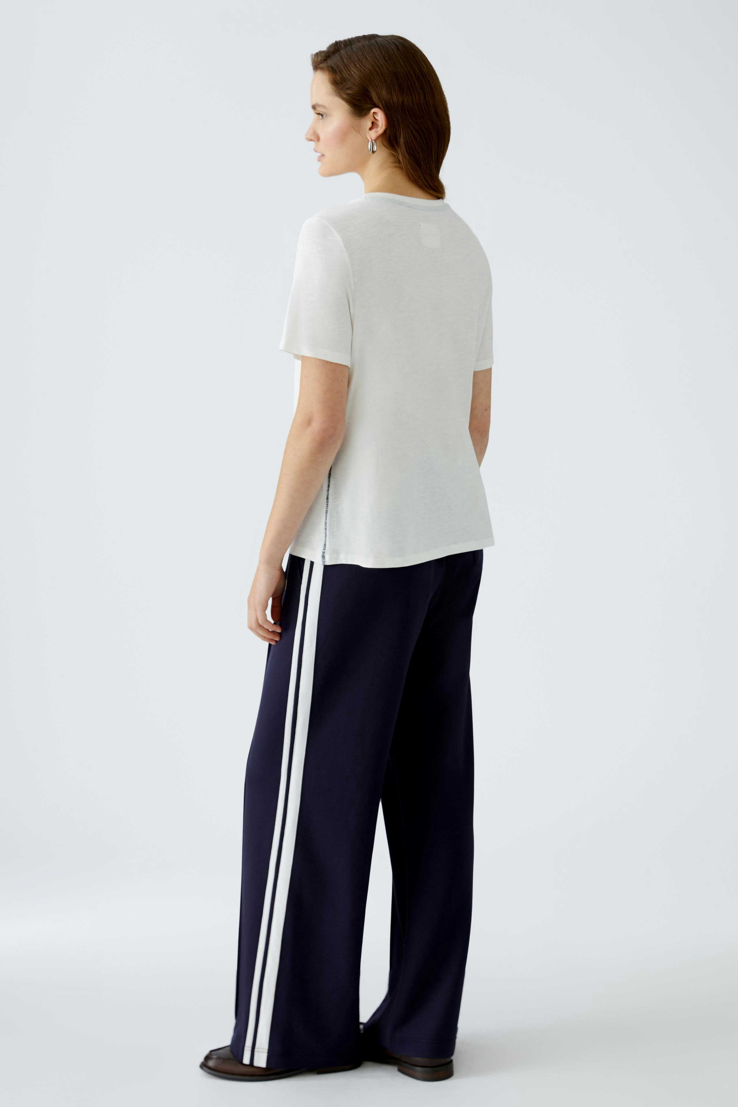 Stylish women's T-shirt: A woman in a light top with a relaxed fit, paired with wide-leg pants.