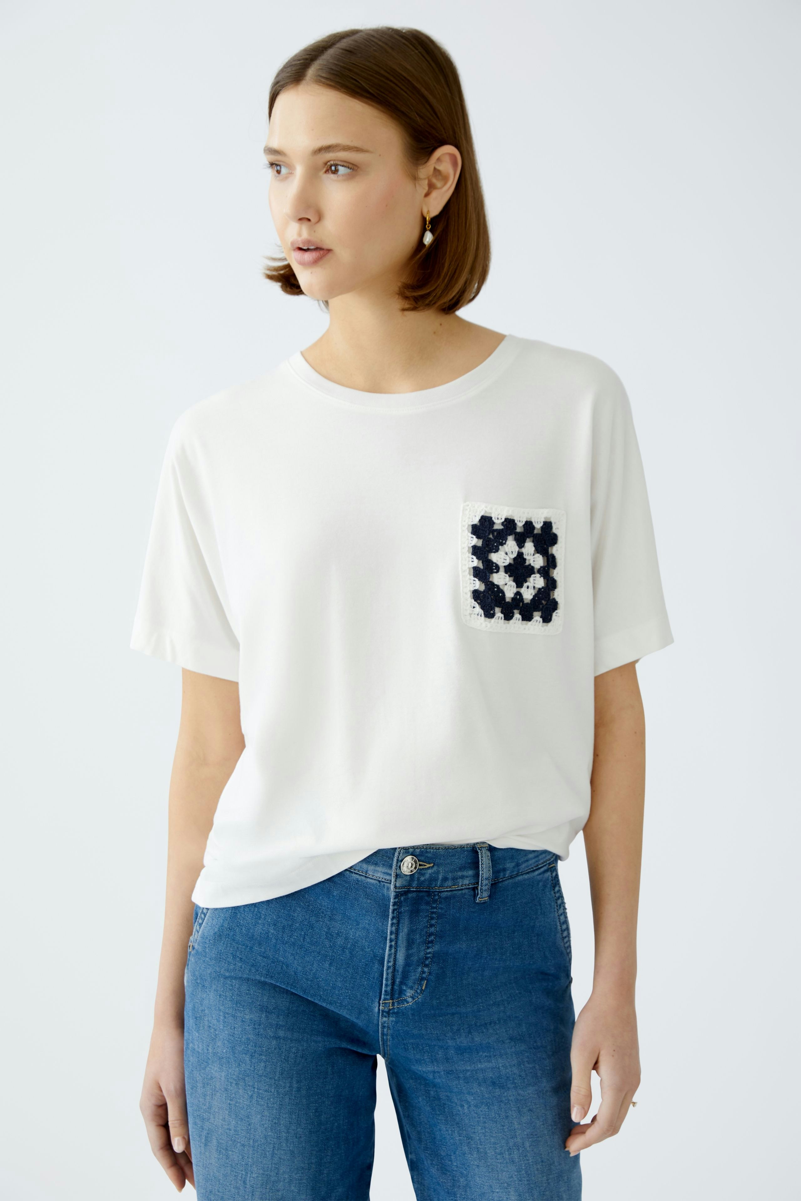 Stylish women's T-shirt: A woman in a white tee with a navy pocket detail, paired with blue jeans.