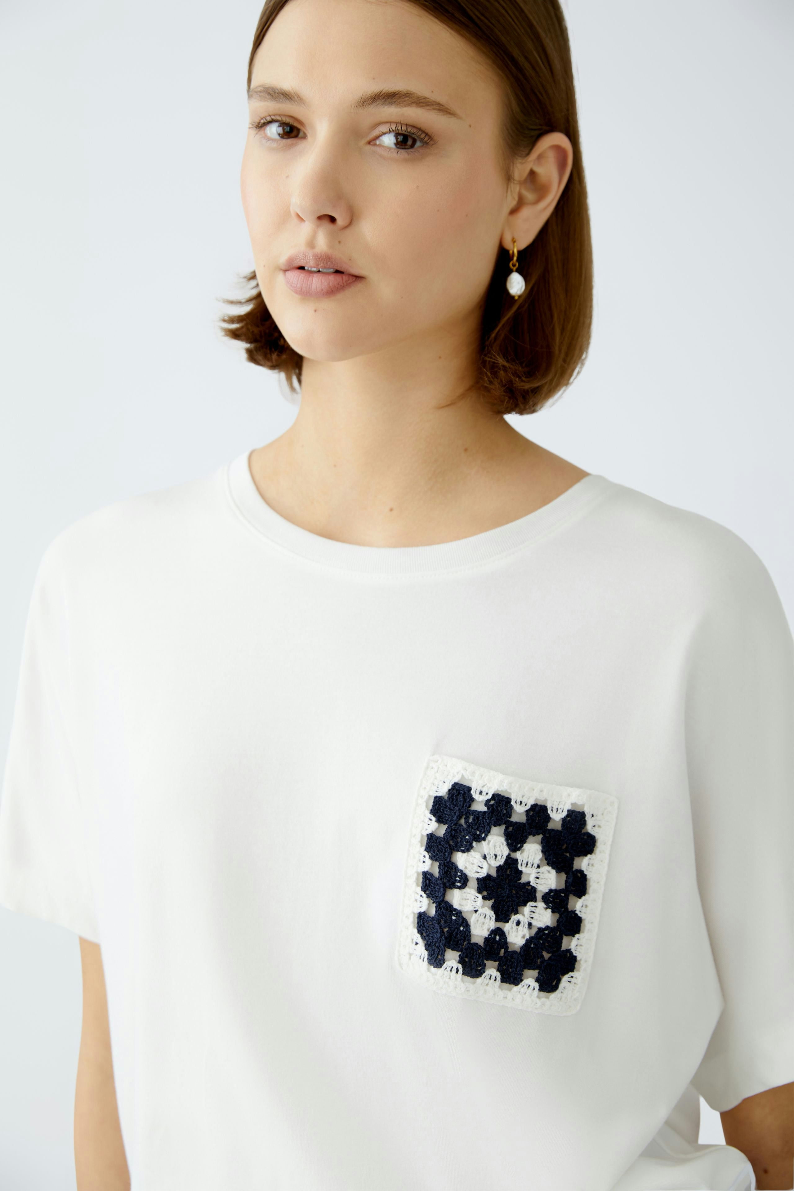 Stylish women's T-shirt: A woman in a white tee featuring a decorative pocket.