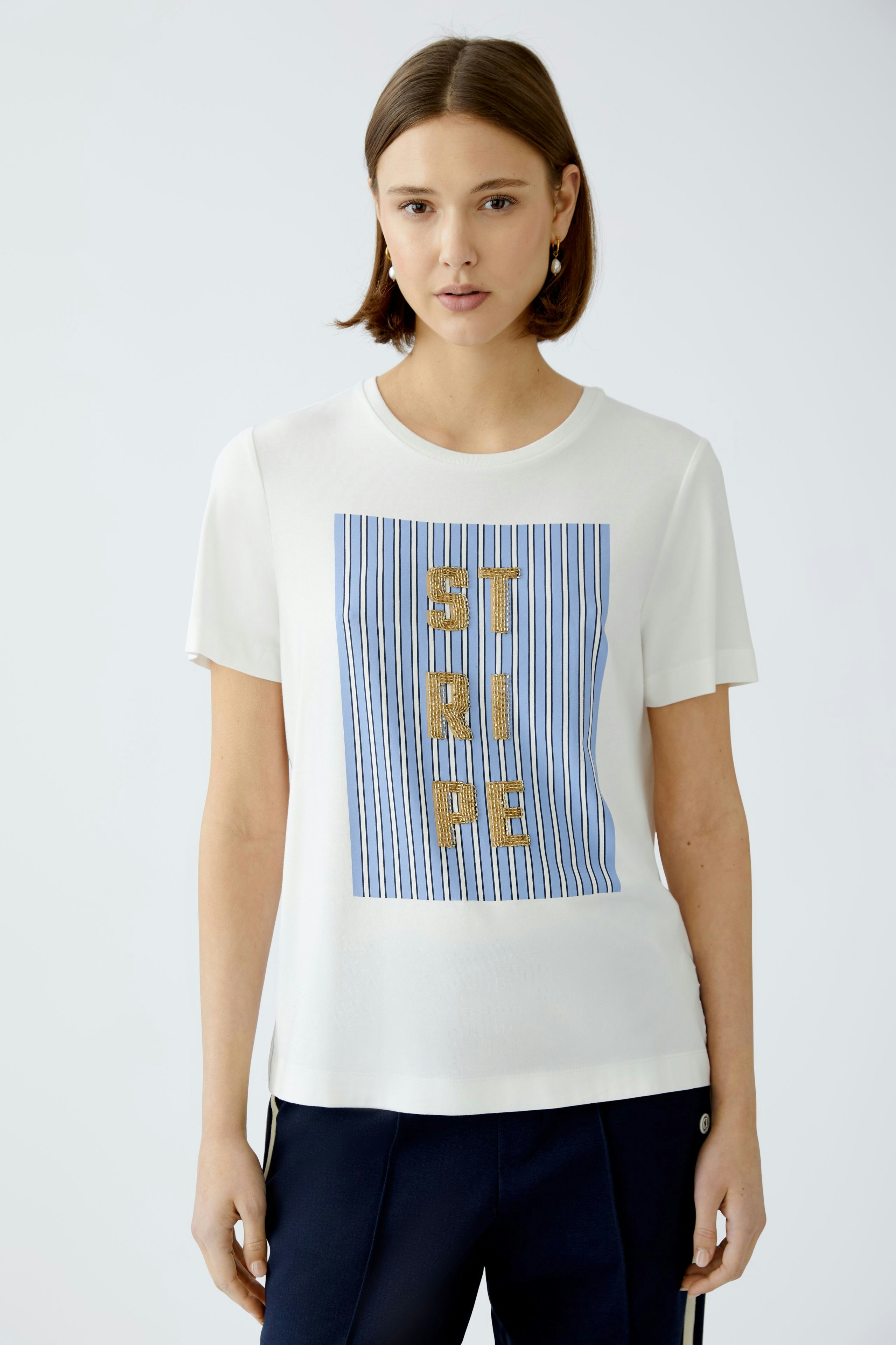 Stylish women's T-shirt: A woman in a white tee with blue stripes and gold lettering.