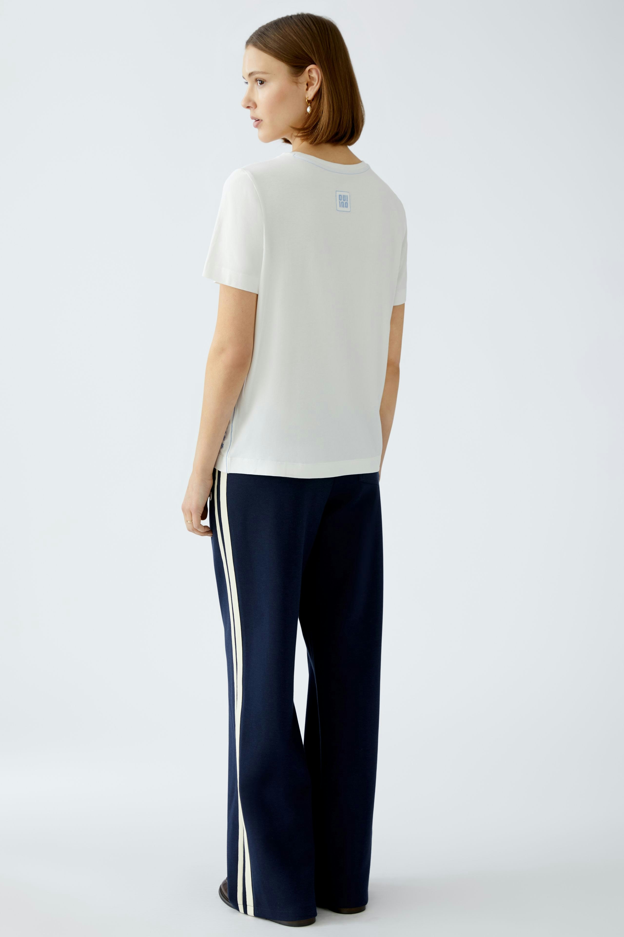 Stylish women's T-shirt: A woman in a white tee paired with navy pants, showcasing a modern look.