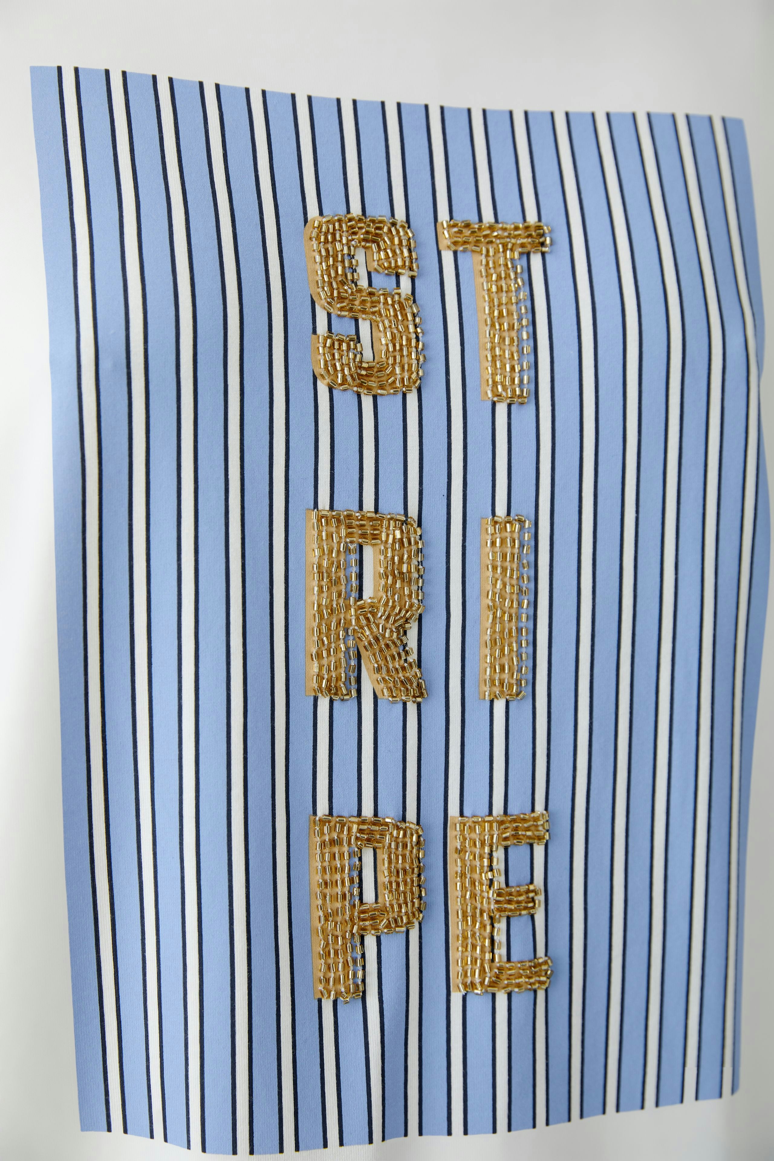 Stylish women's T-shirt: Blue striped design with textured lettering for a modern look.