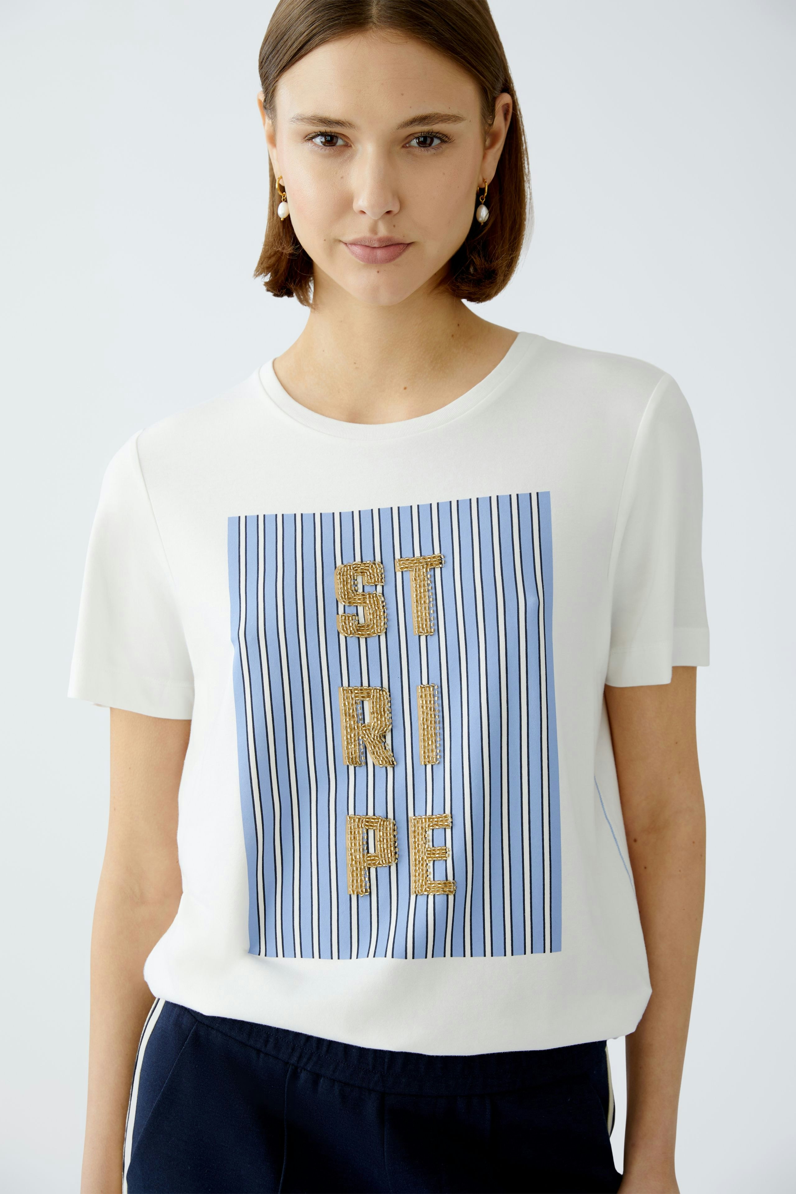 Stylish women's T-shirt: A woman in a white tee with blue stripes and bold lettering, exuding confidence.