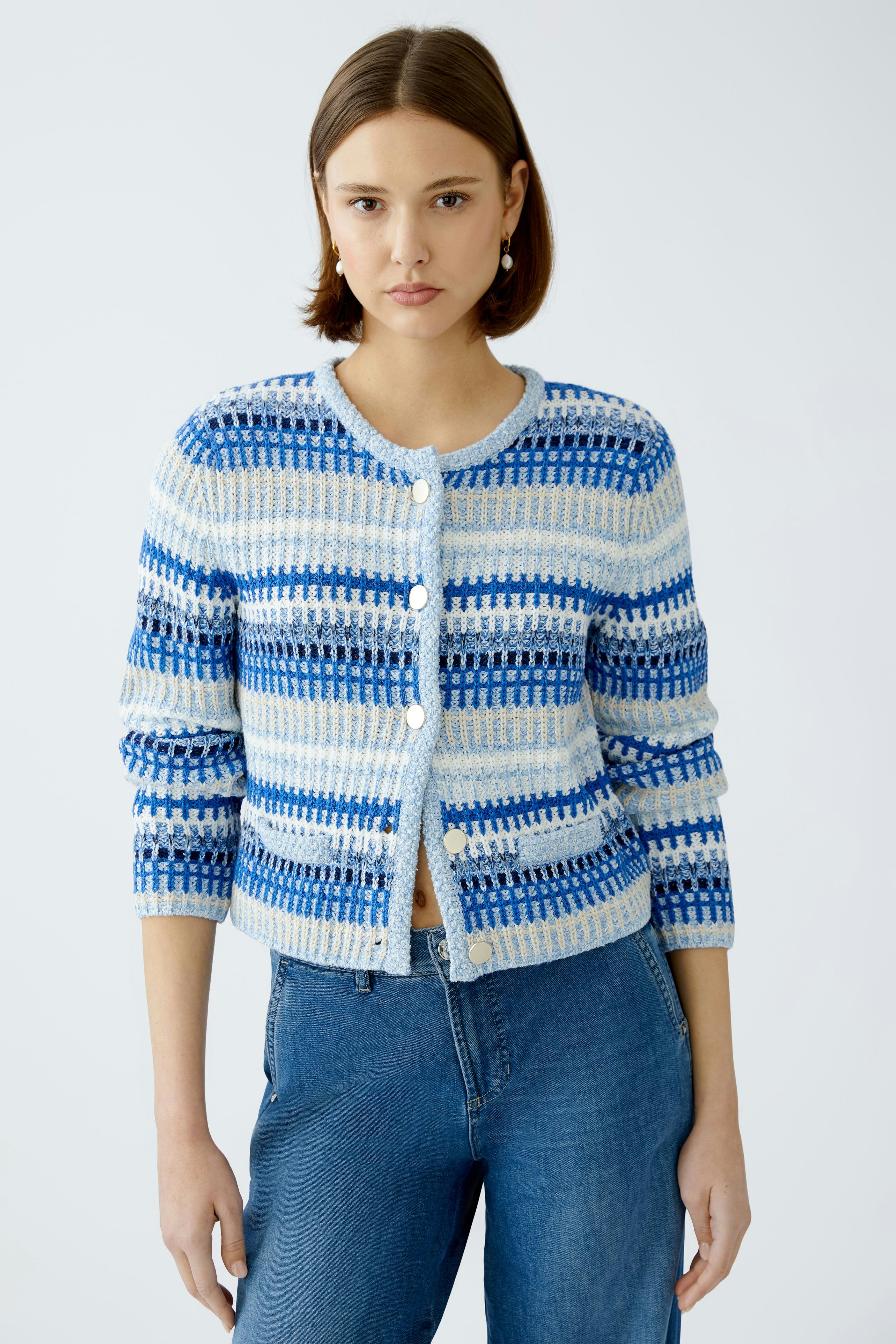 Stylish women's cardigan: A woman in a blue and white striped cardigan, paired with jeans.