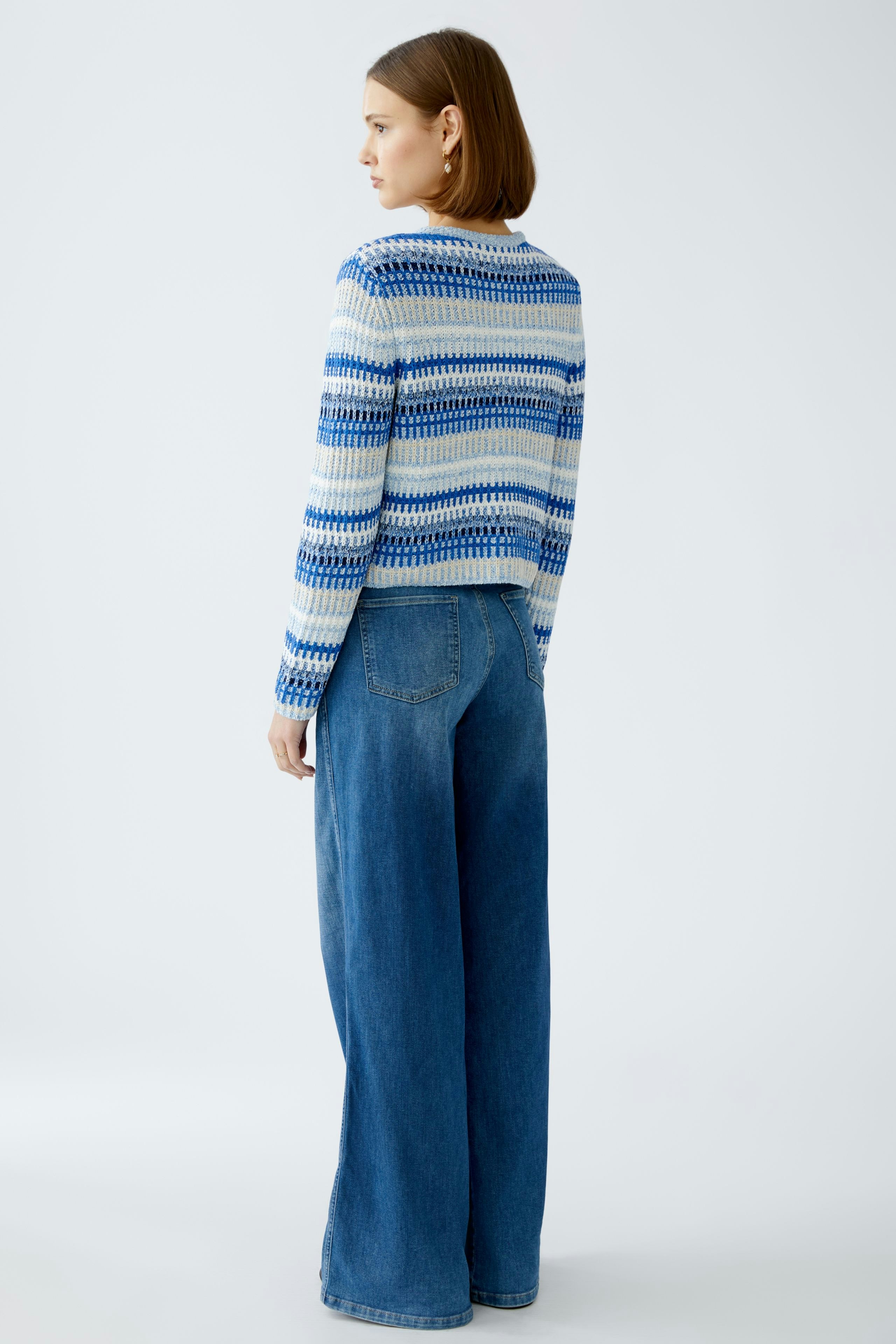 Stylish women's cardigan: A woman in a blue patterned cardigan paired with wide-leg jeans.