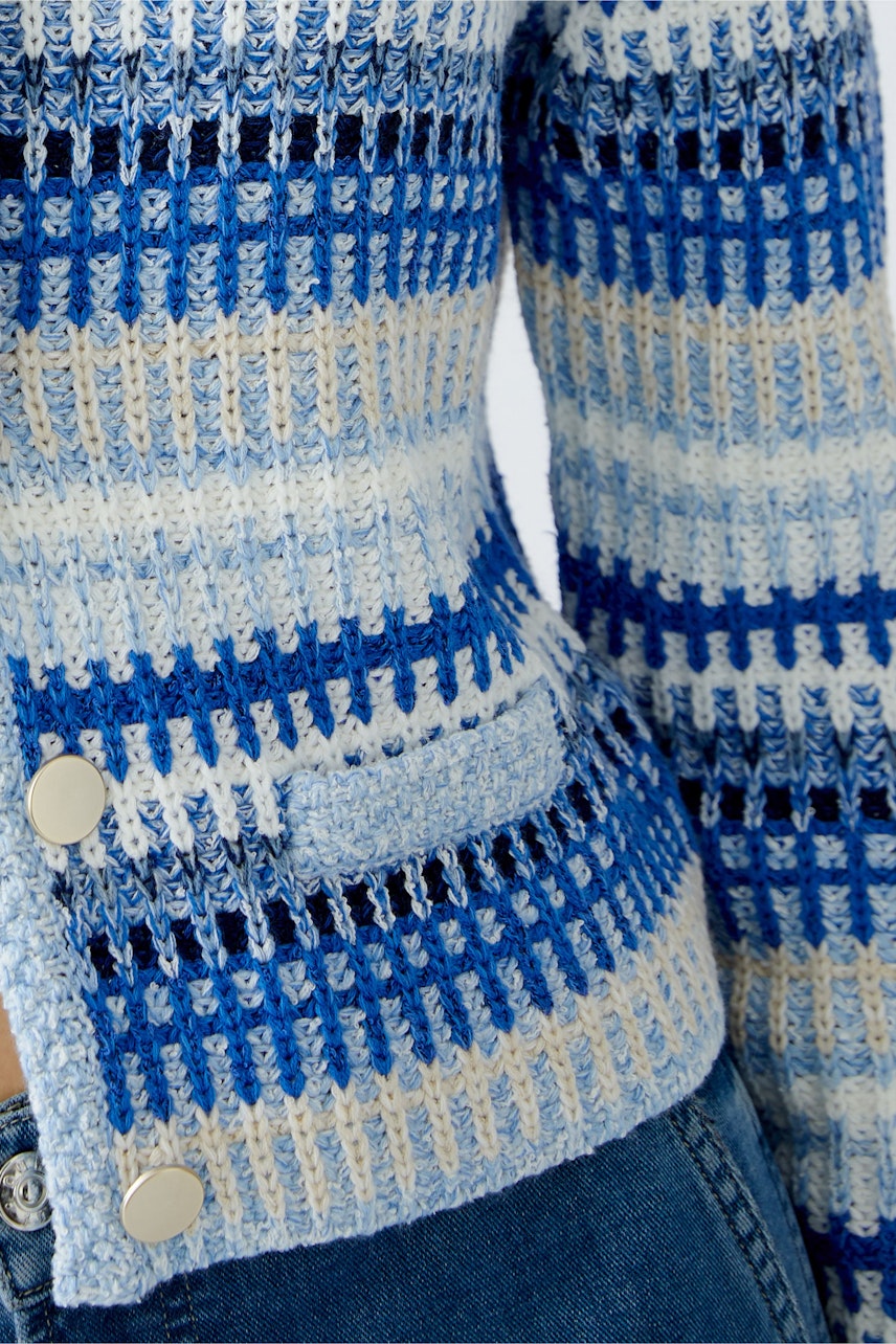 Strickjacke in Blau- und Beigetönen: Detailansicht einer Damen-Strickjacke mit Knöpfen und feinem Muster.