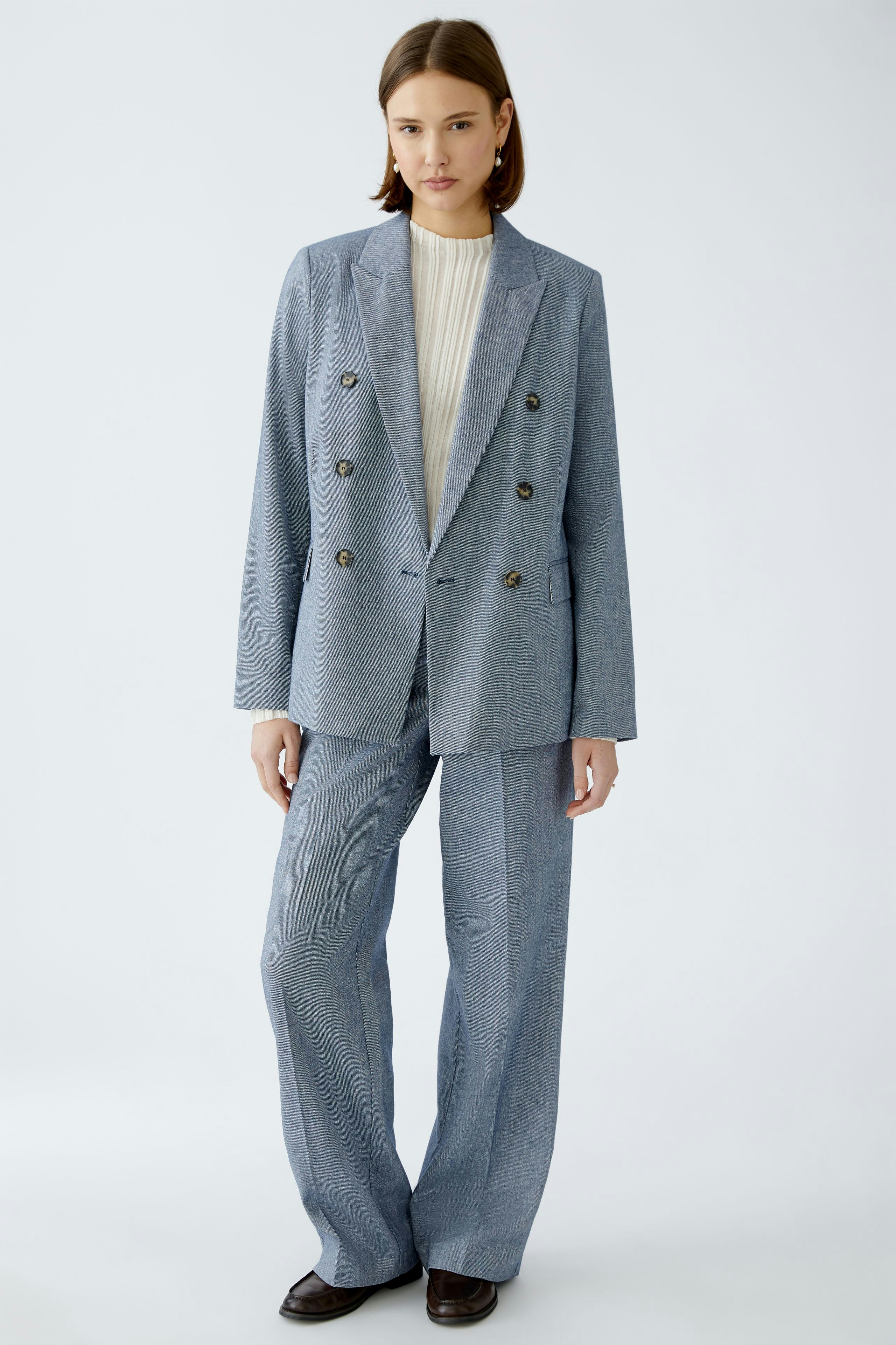 Stylish women's blazer: A woman in a tailored blue double-breasted blazer paired with wide-leg trousers.