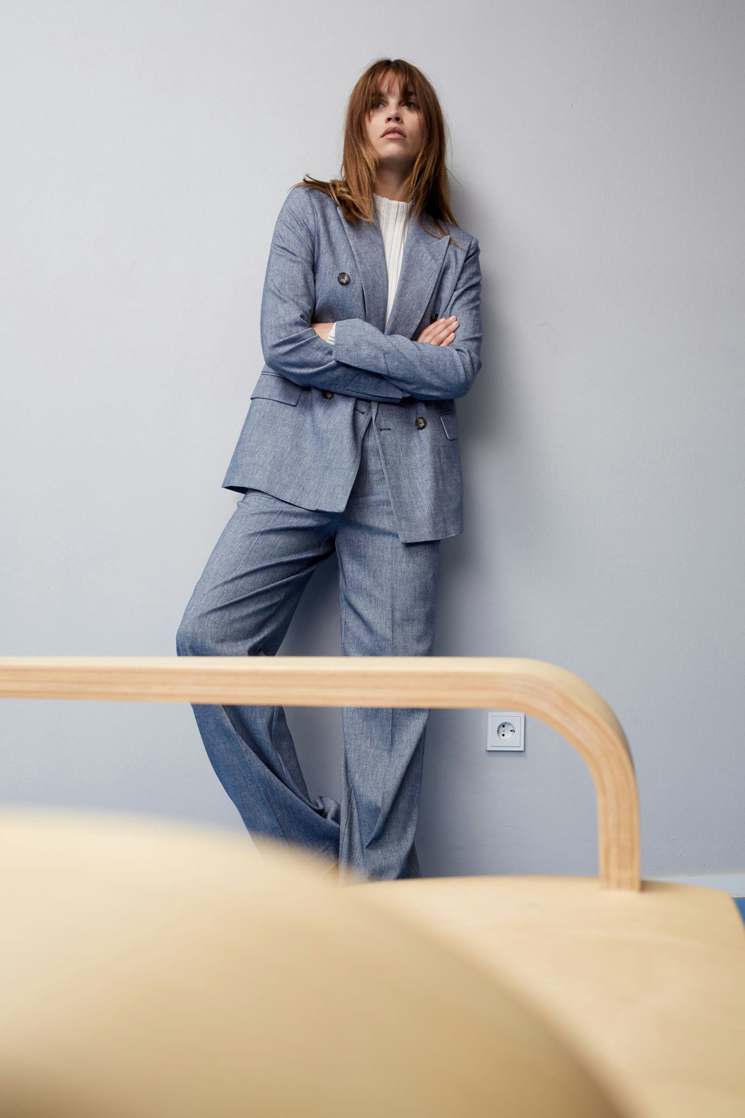 Stylish women's blazer: A woman in a tailored blue blazer and matching trousers stands confidently.