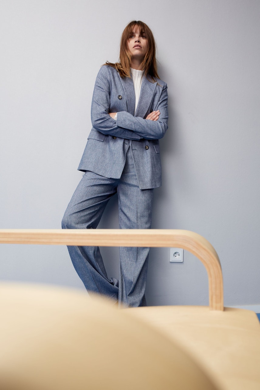 Eleganter Damen-Blazer: Frau in grauem Blazer mit doppelter Knopfleiste und lässiger Pose.