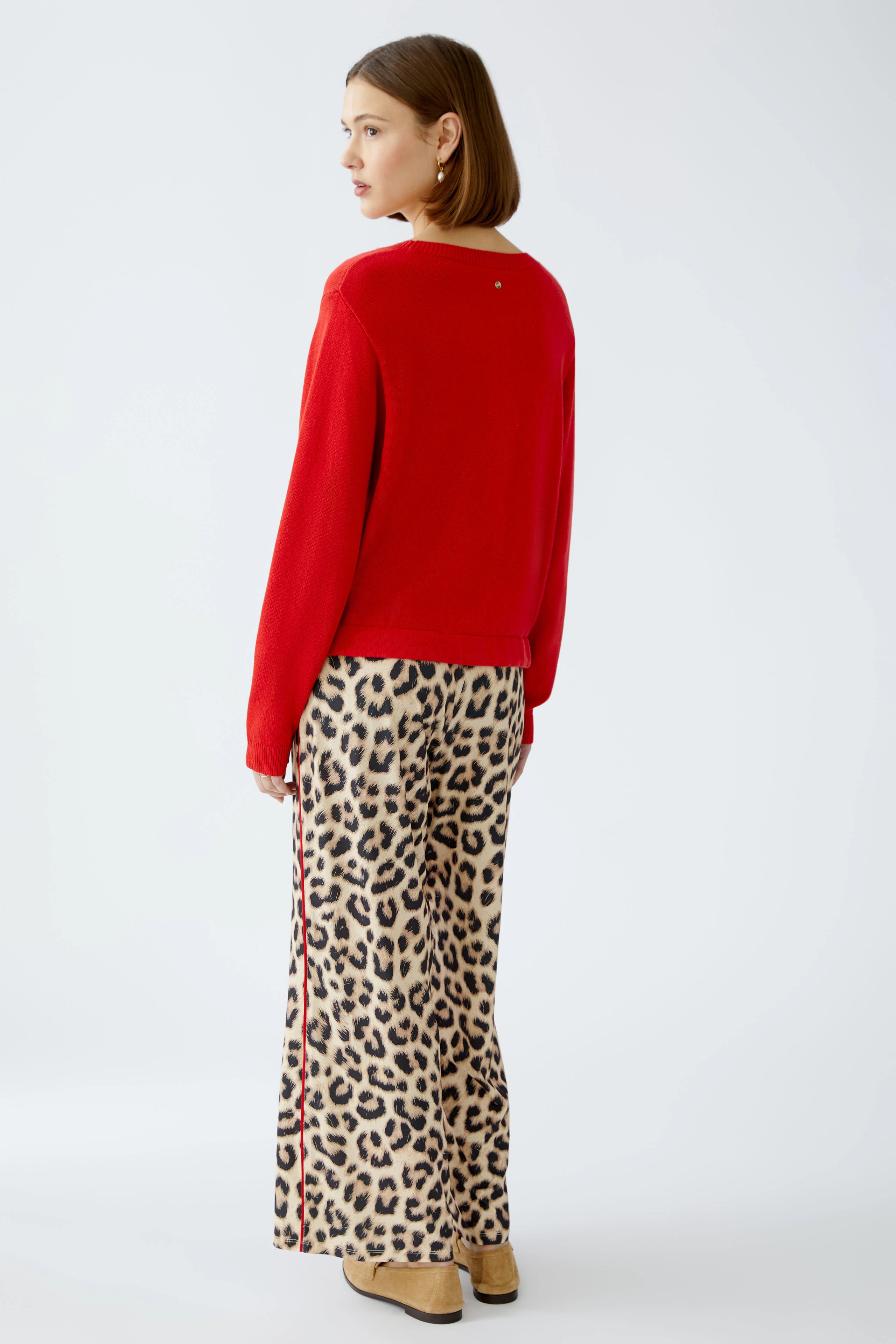 Damen-Pullover: Frau in rotem Pullover mit lässigem Schnitt und animalischem Print-Hosen.