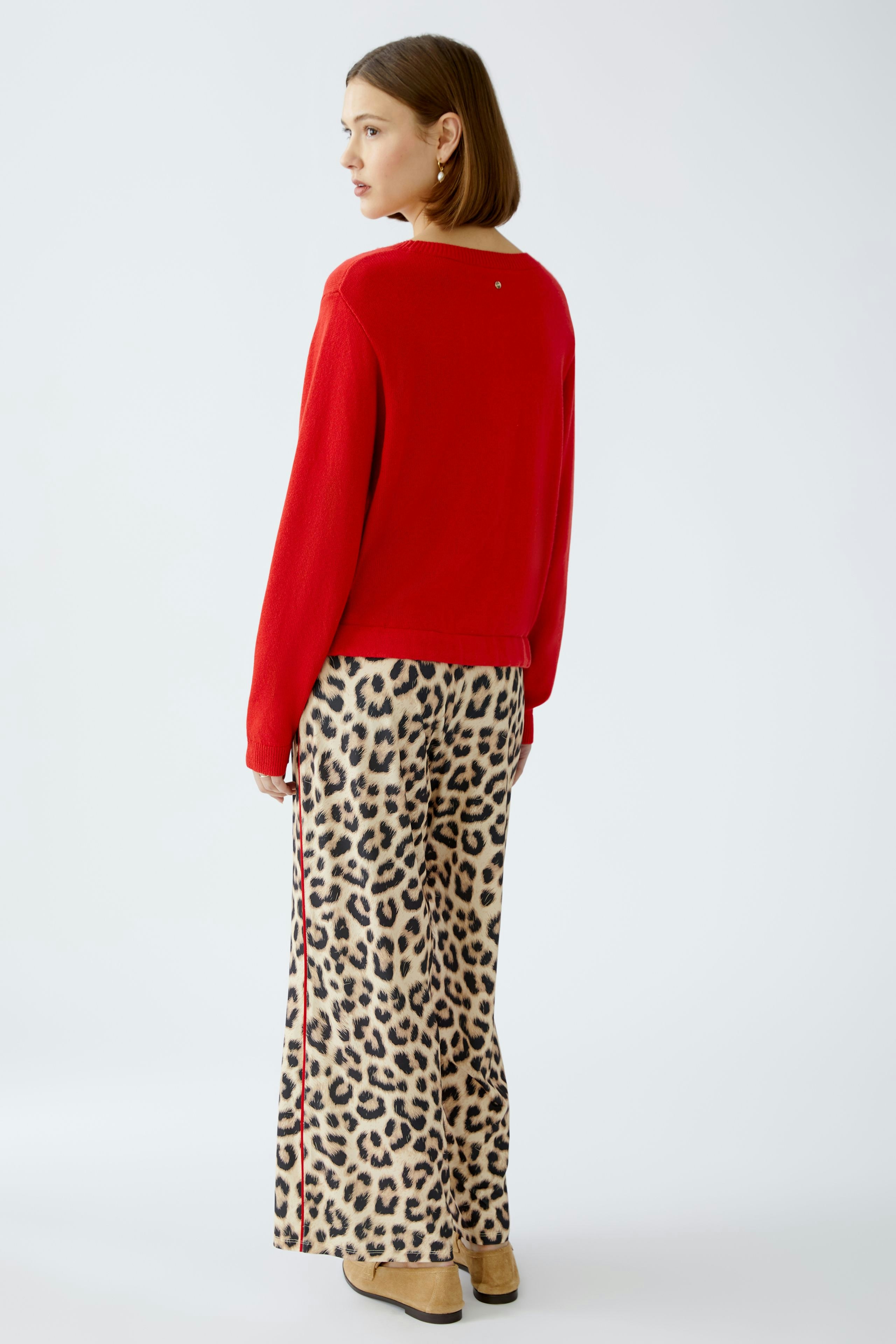Stylish women's pullover: A woman in a red pullover paired with leopard print pants.
