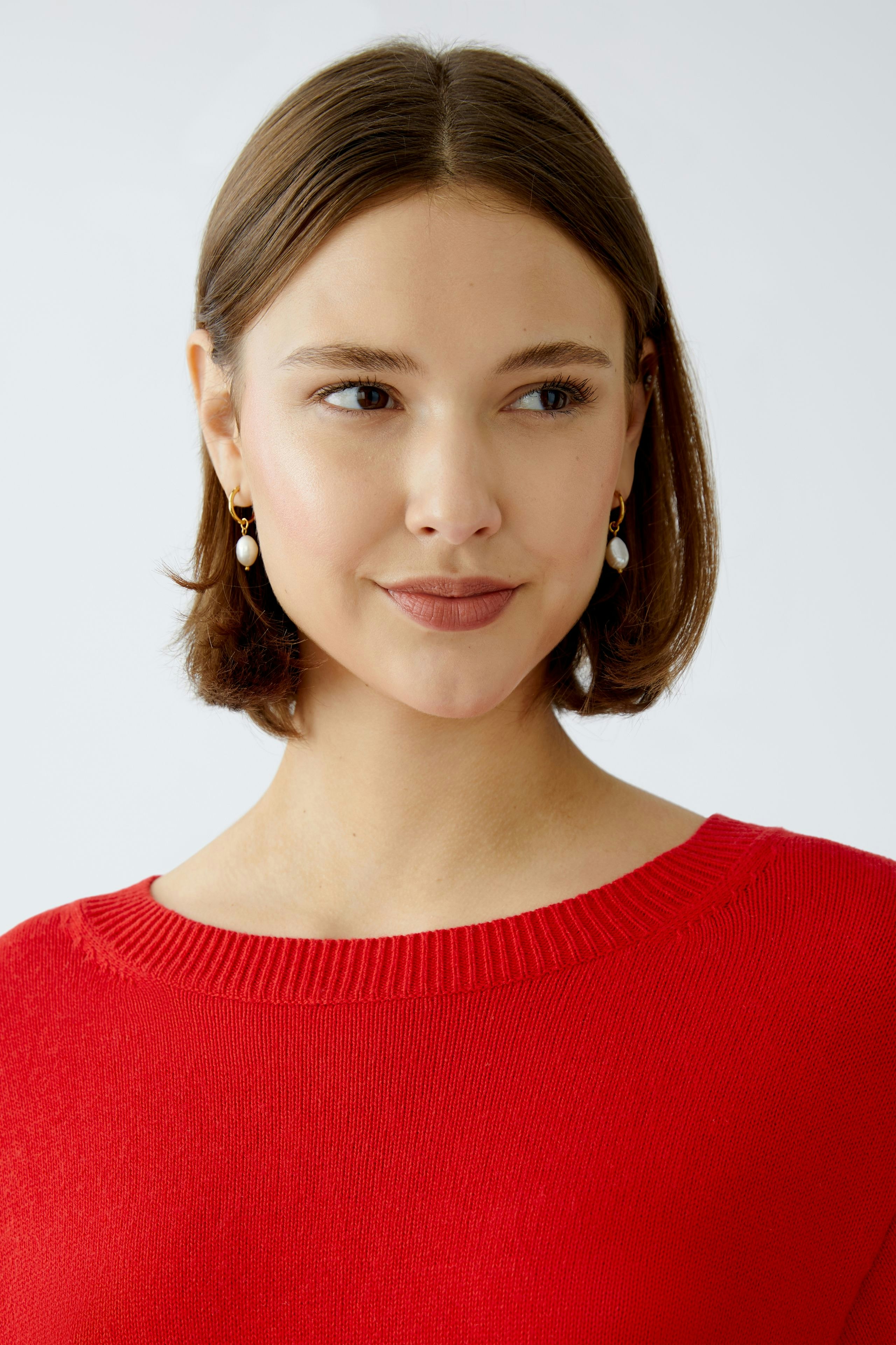 Modern women's pullover: A woman in a vibrant red pullover with a relaxed fit and classic neckline.