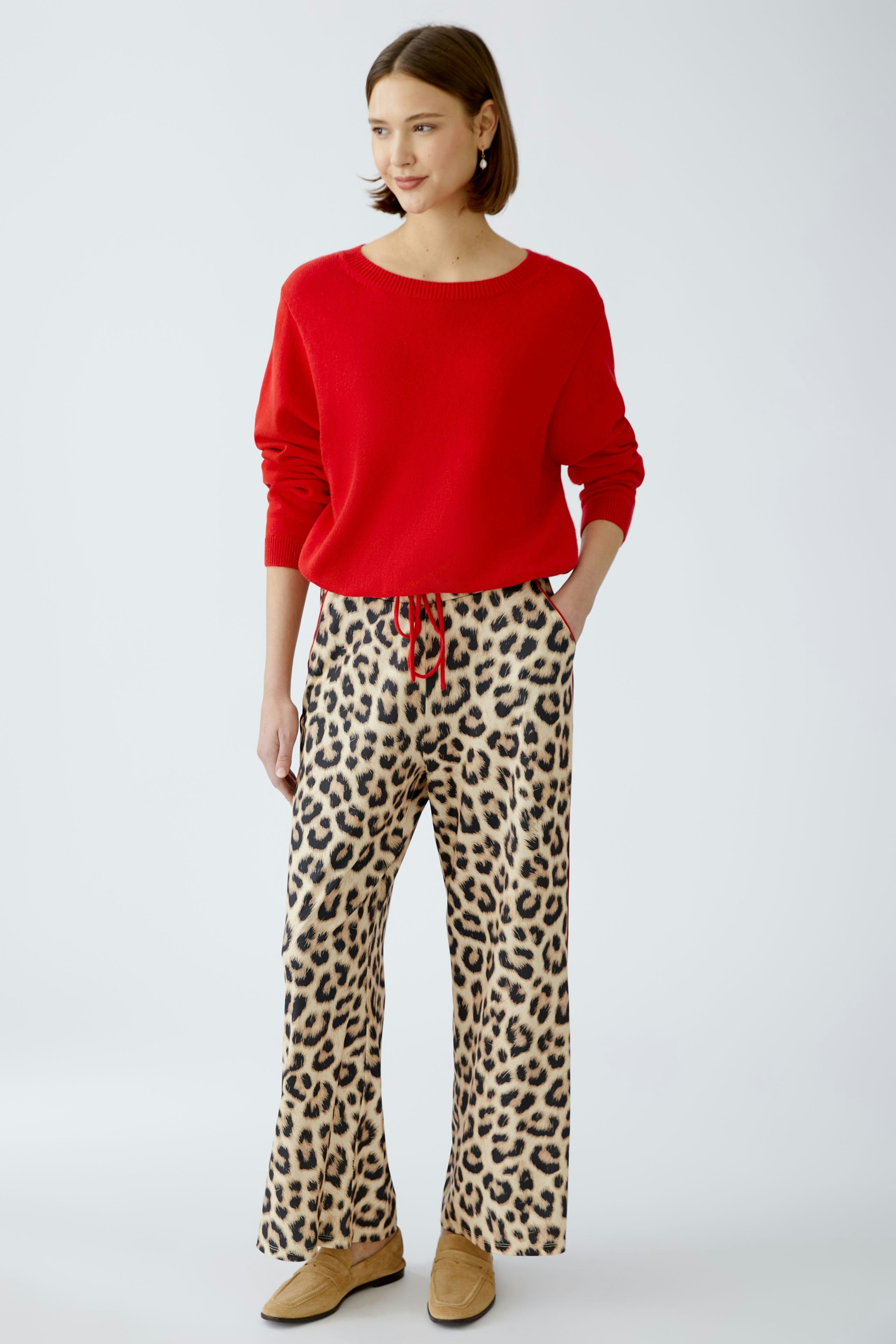 Stylish women's pullover: A woman in a red pullover paired with leopard print pants, exuding confidence.