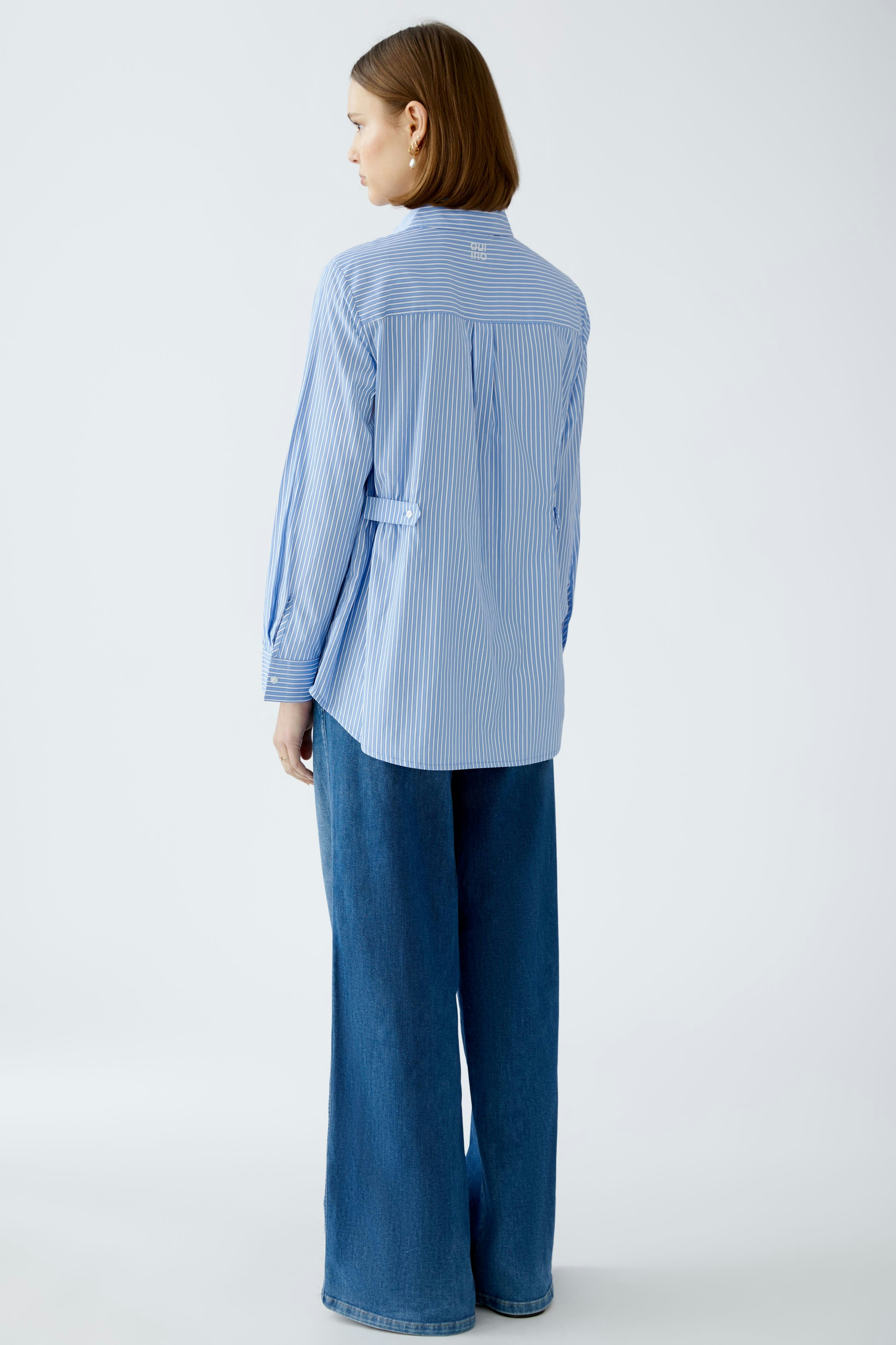 Stylish women's blouse: A woman in a blue striped blouse with a relaxed fit and elegant design.