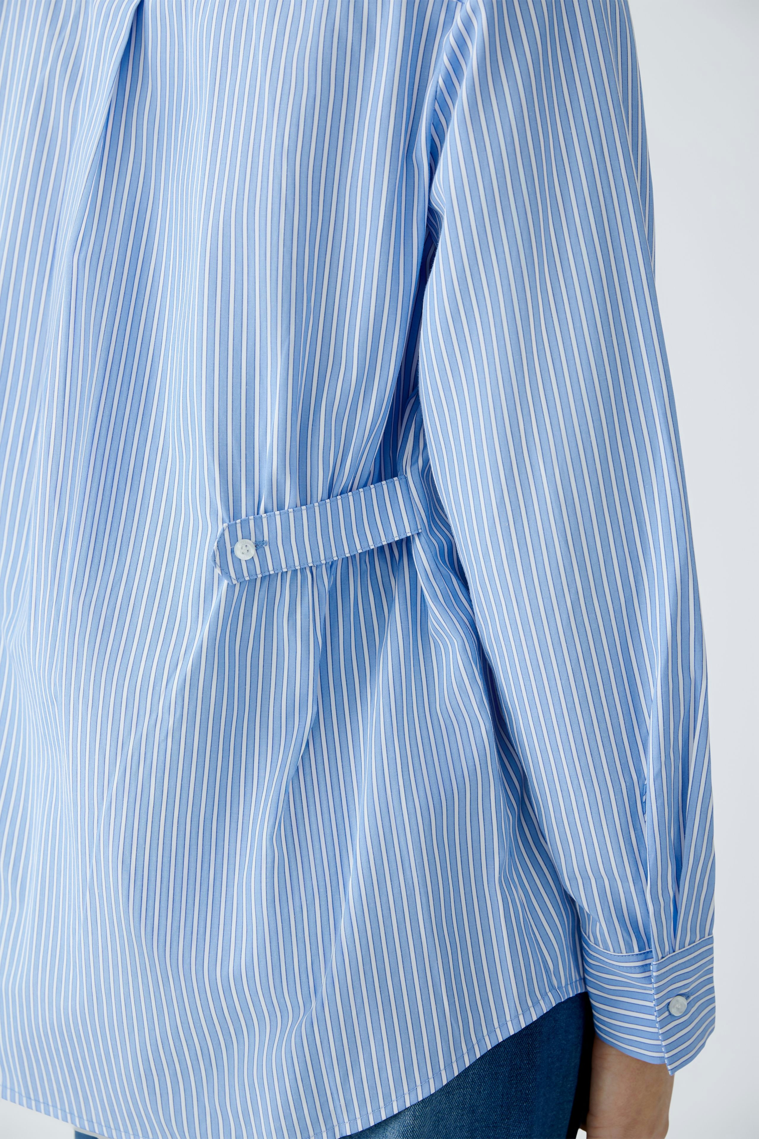 Stylish women's blouse: A woman in a blue striped blouse with a relaxed fit and elegant details.