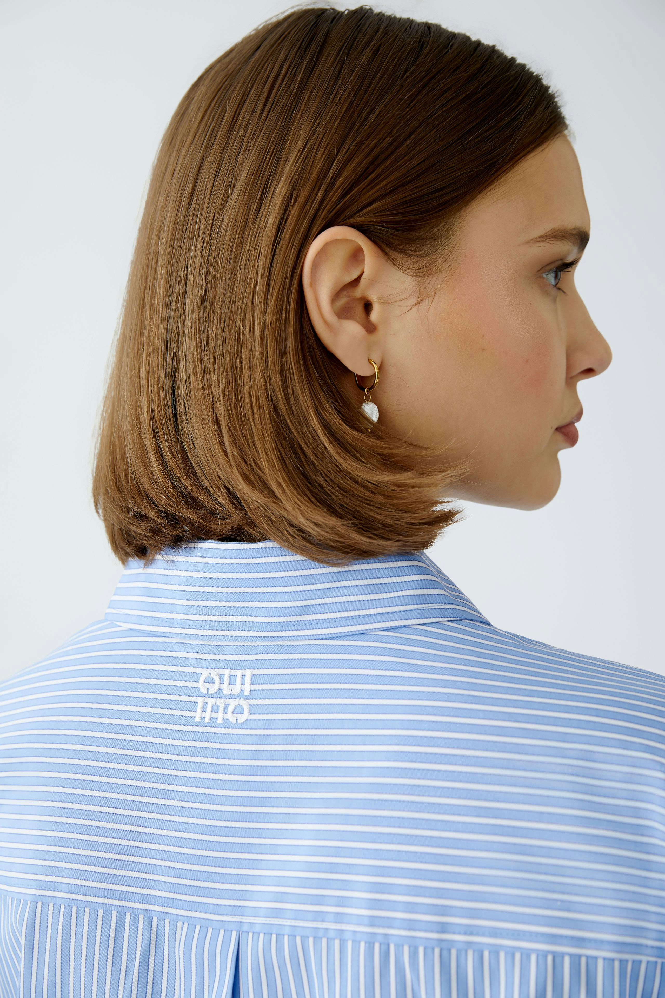 Stylish women's blouse: A woman in a light blue striped blouse with a classic collar.