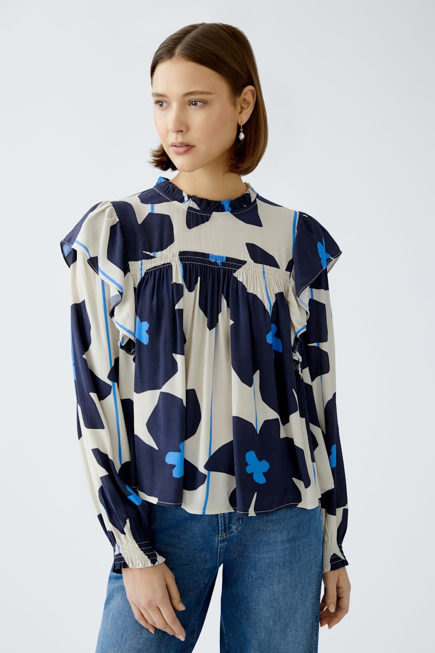 Stylish blouse: A woman in a floral-patterned blouse with ruffled details and relaxed fit.