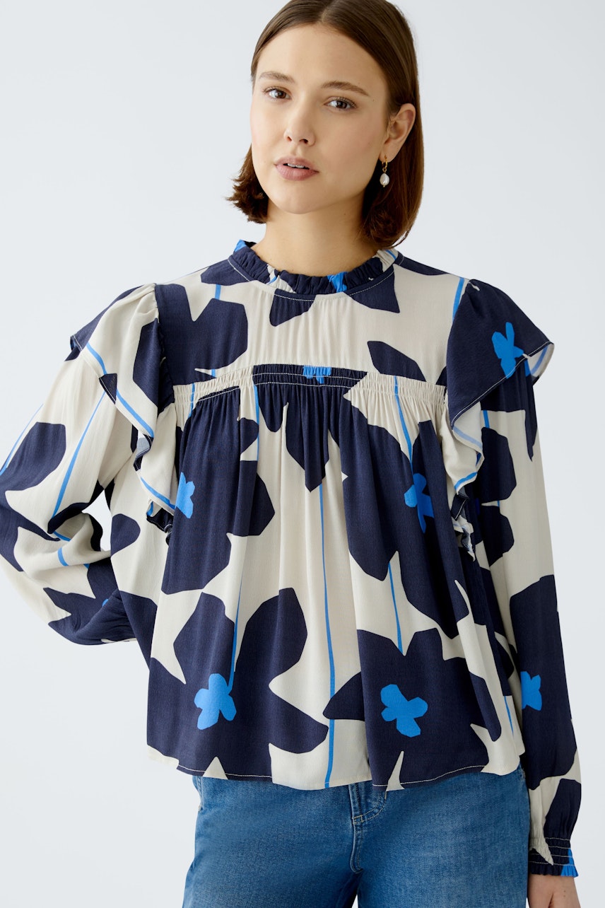 Stylish women's blouse: A woman in a floral-patterned blouse with ruffles and a relaxed fit.